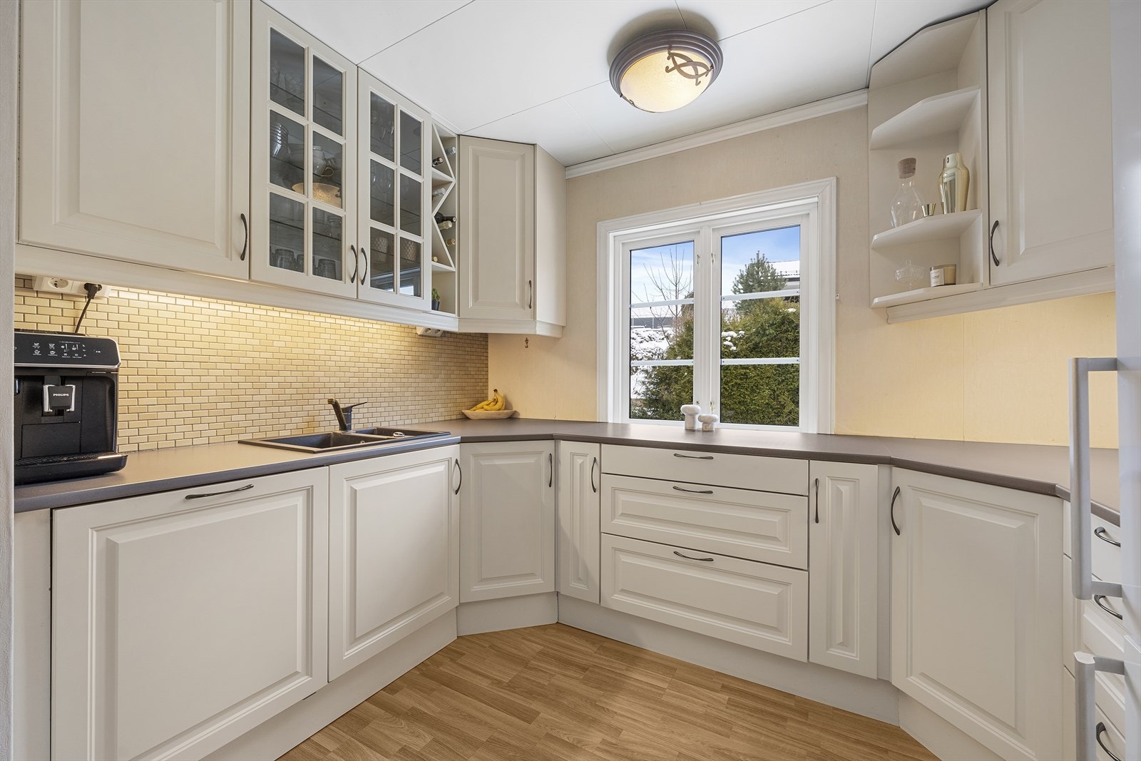 Pent kjøkken med hvite, profilerte fronter og laminert benkeplate Galleribilde