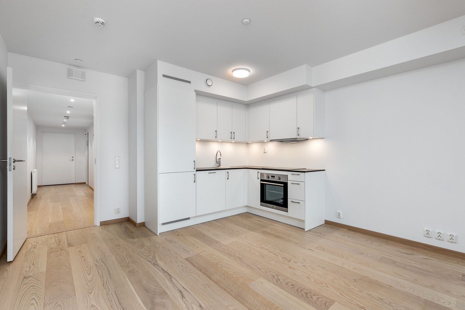 Lekkert kjøkken utformet i vinkel, med integrerte hvitevarer. Galleribilde