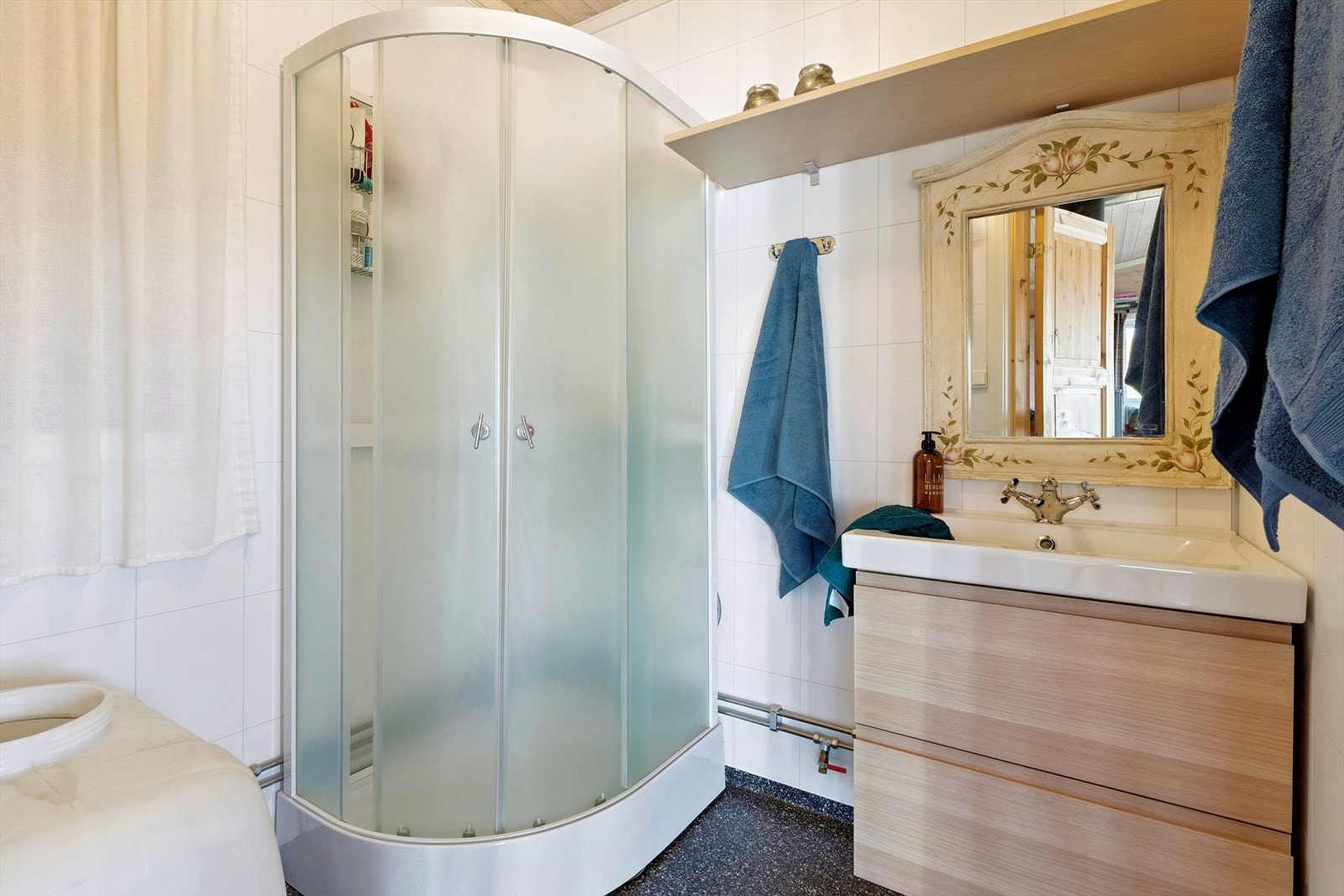 Badet er utstyrt med dusjkabinett, servantinnredning og har vinylbelegg på gulv. Galleribilde