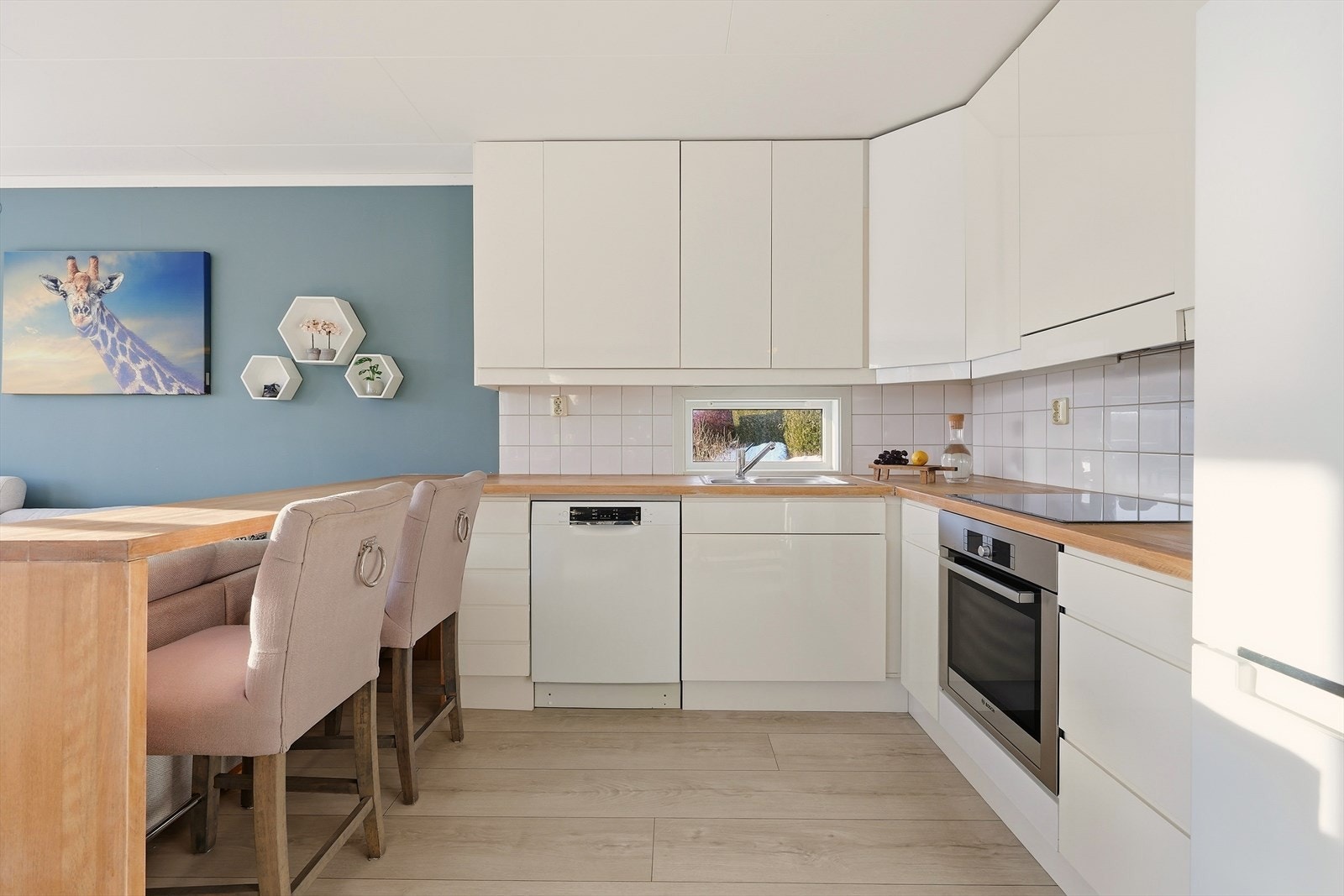 Pent og moderne kjøkken med glatte fronter, flislagt over kjøkkenbenk og benkeplate i heltre Galleribilde