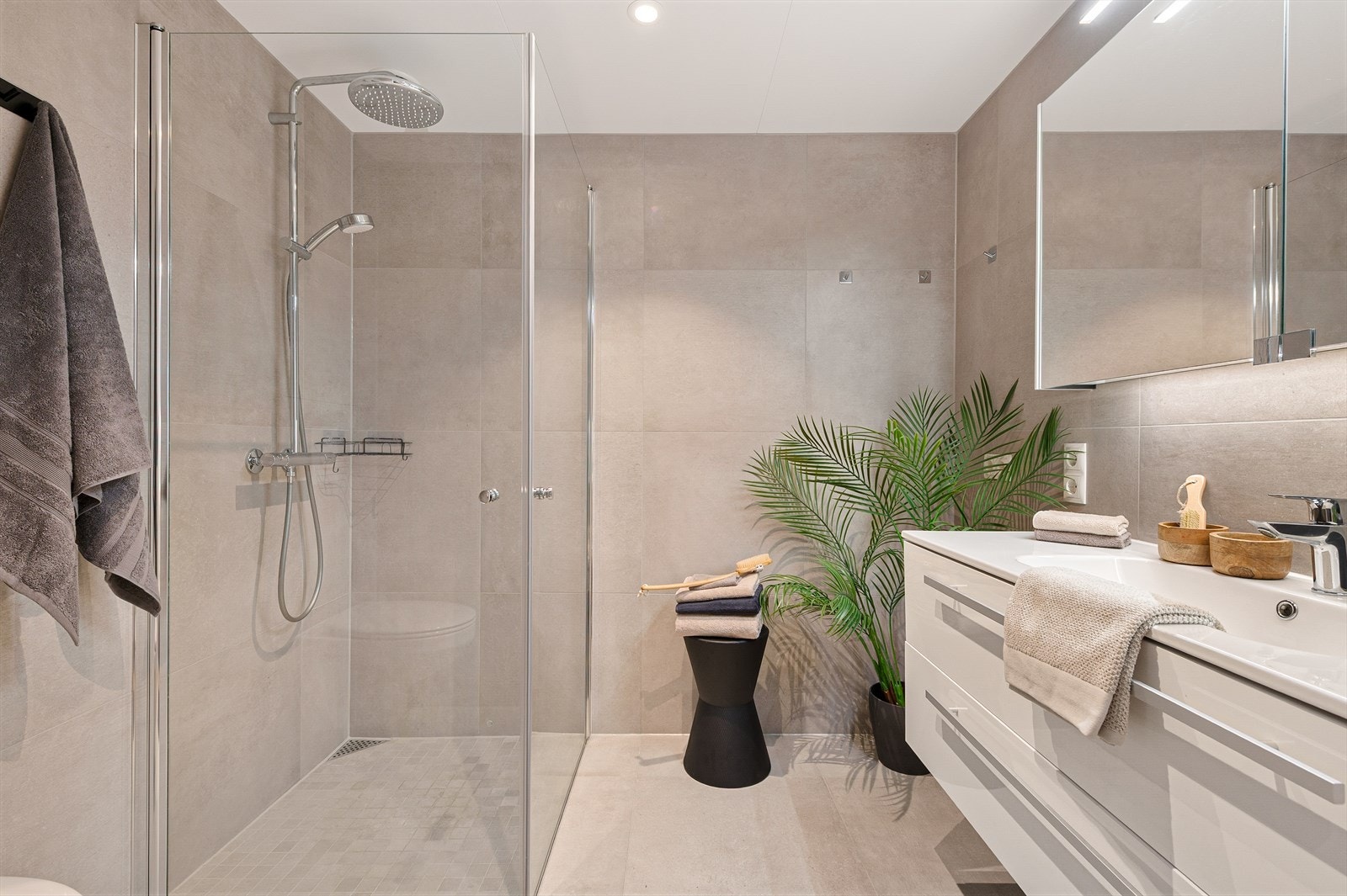 Badet er innredet med dushjørne, vegghengt toalett, servant og skapspeilt. Opplegg for vaskemaskin. Galleribilde