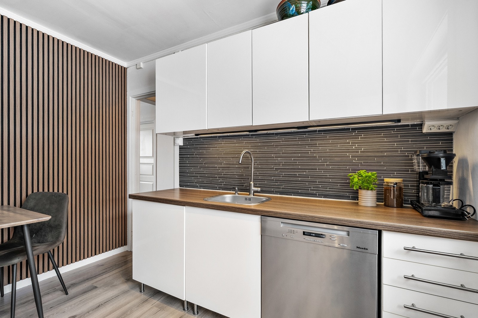 Overflatene på kjøkkenet har laminat på gulvet, lyse veggoverflater og en lekker spilevegg på kortsiden. Galleribilde