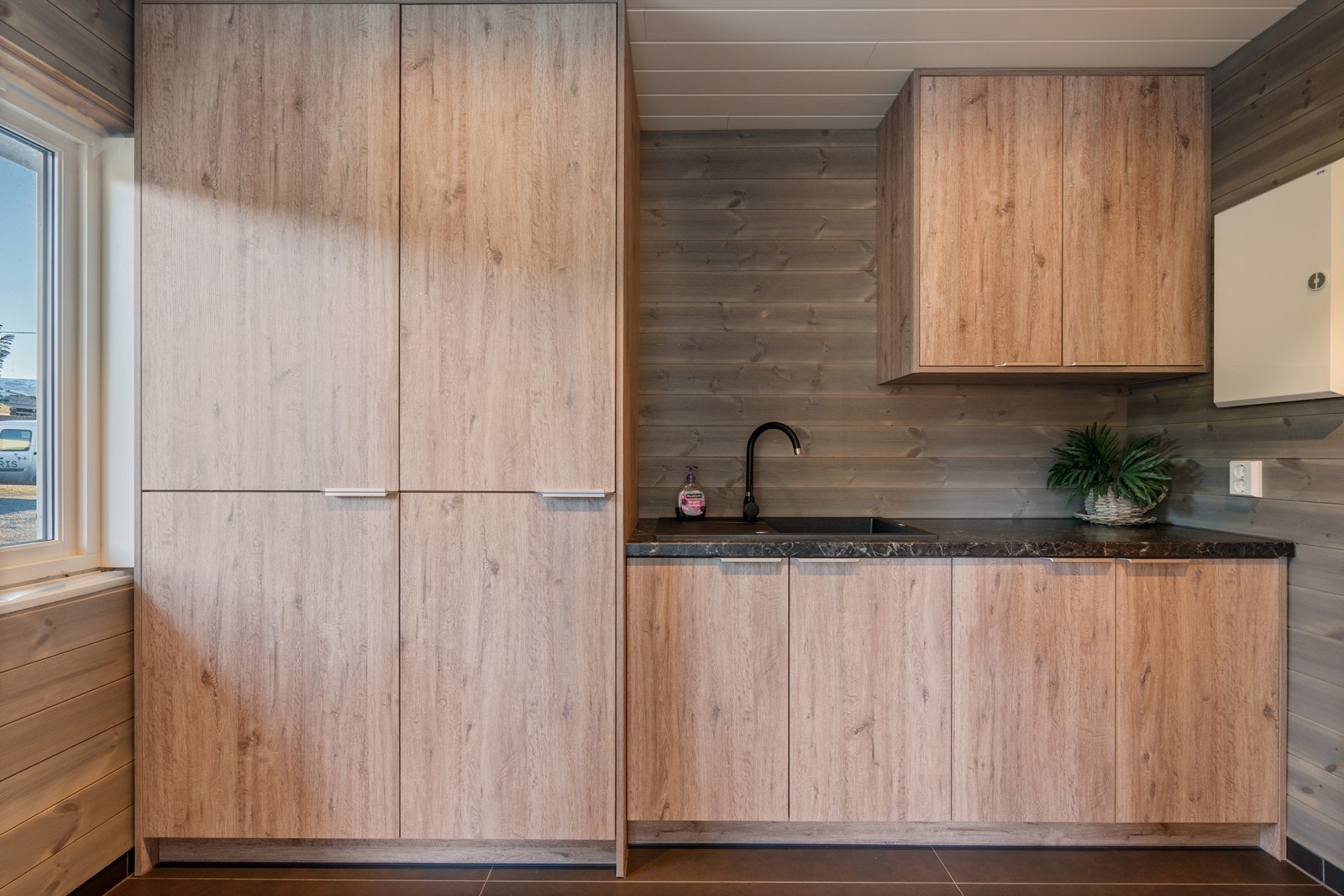 Nyoppusset og funksjonelt vaskerom med flislagt gulv og varmekabler. Rommet er innredet med flott innredning i trelook med rikelig skap- og oppbevaringsplass. Galleribilde