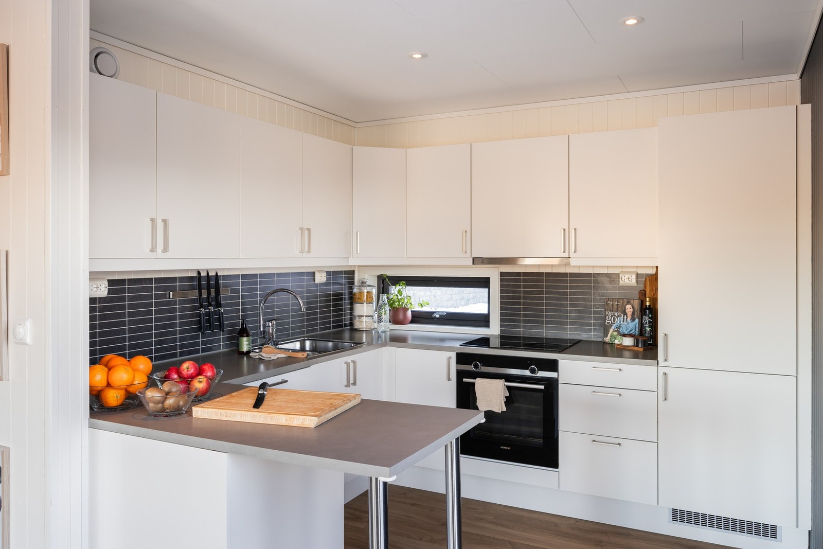 Kjøkkenet er lyst, delikat og har downlights i tak. Innredningen på kjøkkenet består av foliert skrog, lakkerte fronter og laminerte benkeplater. Galleribilde