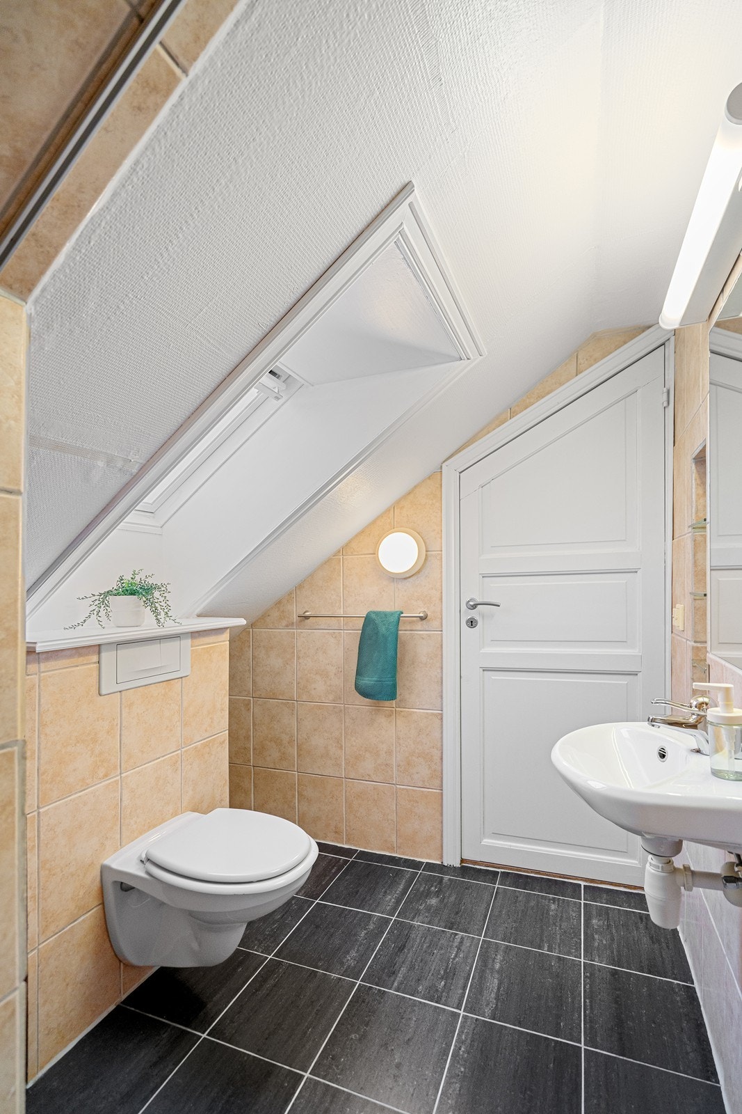 Flisebelagt bad er innredet med vegghengt toalett, vask og dusjhjørne. Galleribilde