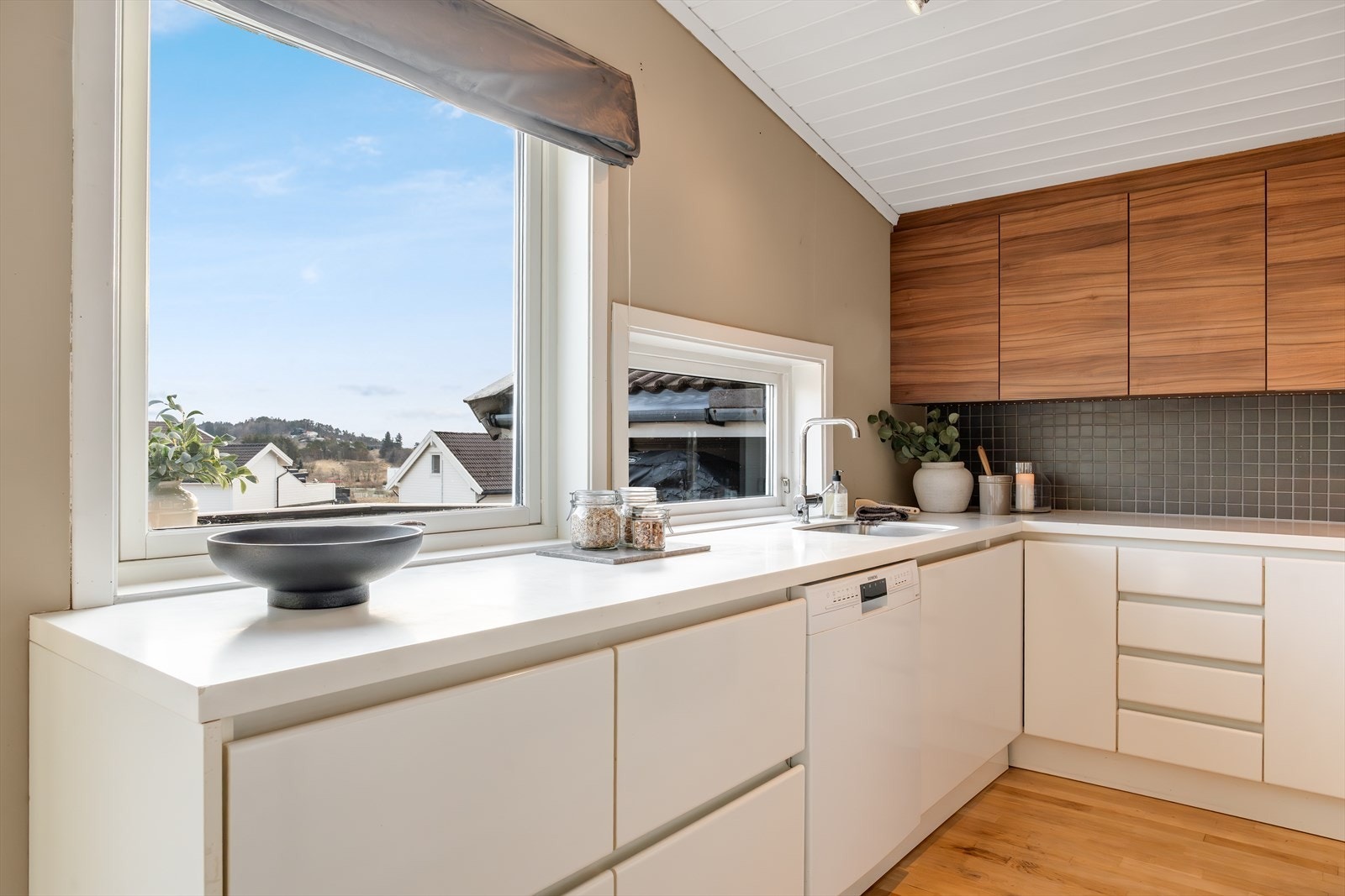 Flott kjøkken utført med slette fronter, takhøye overskap på den ene veggen og benkeplate med nedfelt vask. Galleribilde