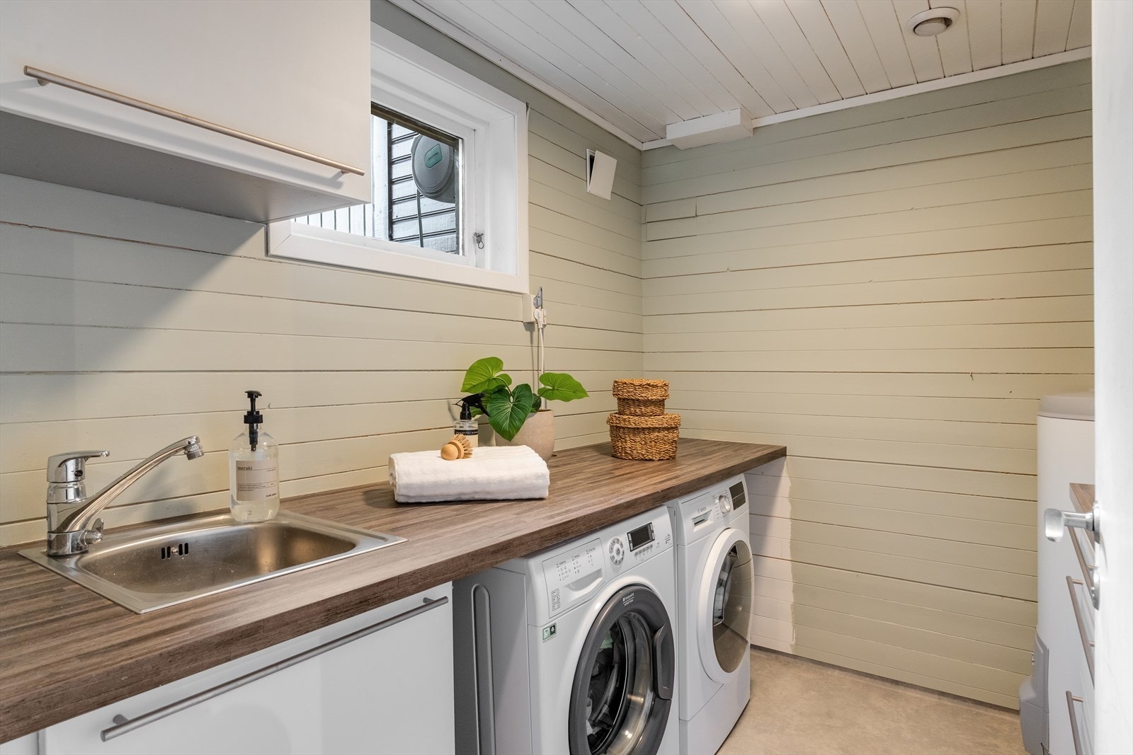 Separat vaskerom som inneholder skap - og benkeinnredning med opplegg for vaskemaskin og tørketrommel. Galleribilde