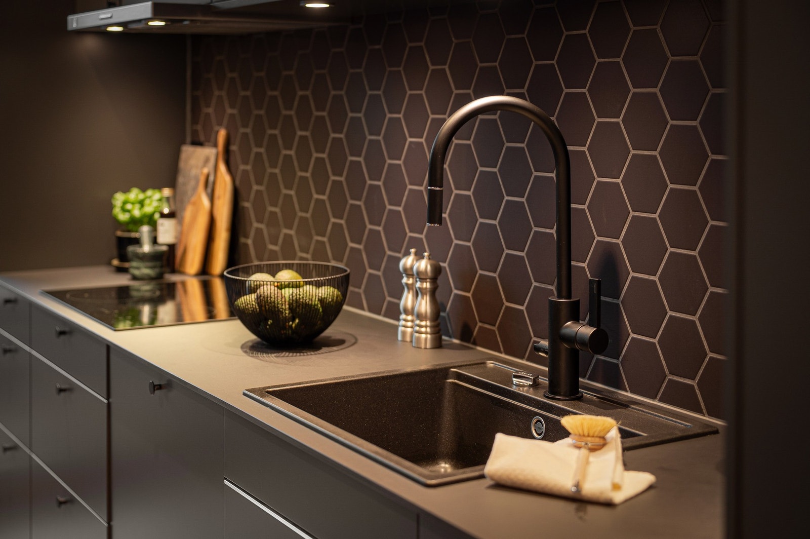 Stilrent Sigdal-kjøkken med hexagonfliser, matt sort armatur og integrerte hvitevarer. Galleribilde