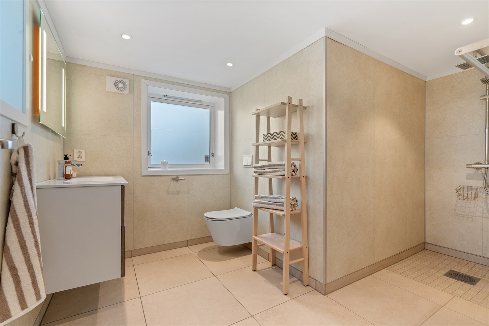 Rommelig bad på grunnplan med baderomsseksjon, dusjnisje og vegghengt toalett Galleribilde