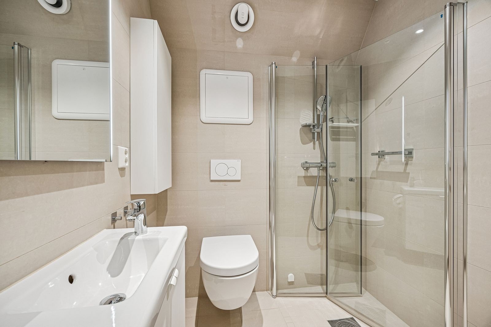 Nylig renovert bad med lyse fliser, vegghengt wc, dusjnisje og servant. Galleribilde