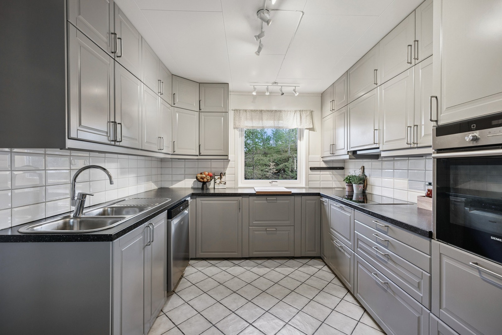 Kjøkkenet har innredning med glatte fronter og benkeplate av laminat Galleribilde