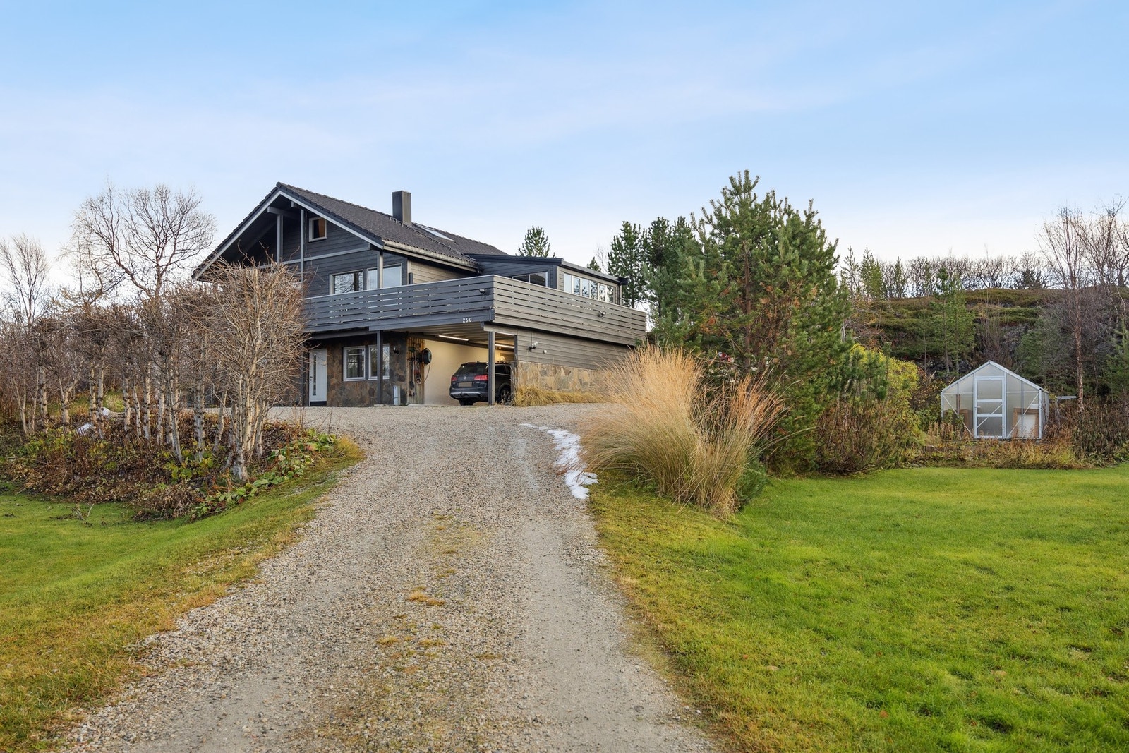 Eiendommen har en stor og pent opparbeidet tomt med plen, busker, trær og gruslagt gårdsplass Galleribilde