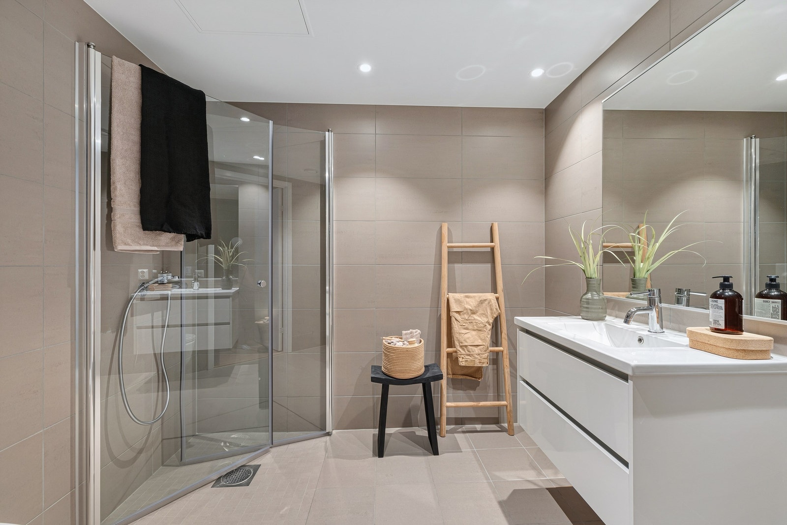 Delikat, flislagt bad med vegghengt toalett og dusjhjørne med innfellbare glassdører. Galleribilde