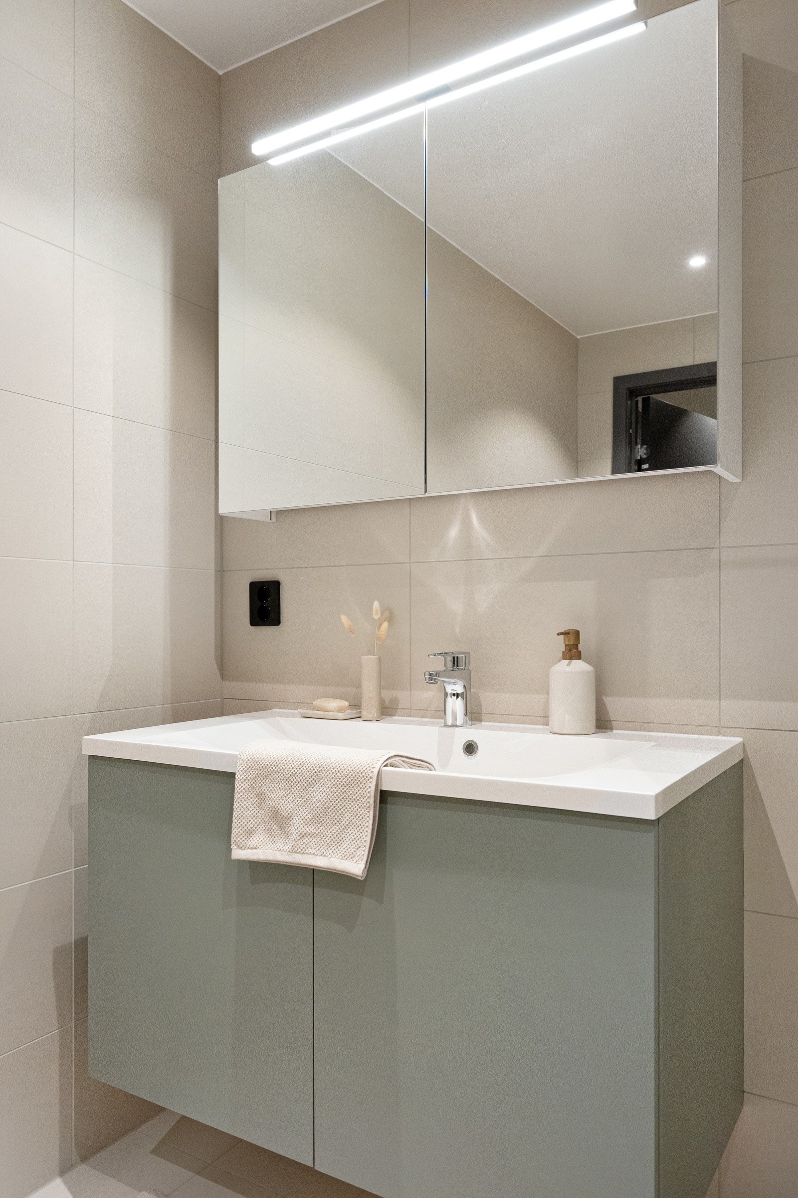 Badet er innredet med dusjhjørne med glassdører, nedfelt vask med skapseksjon og speilskap. Galleribilde