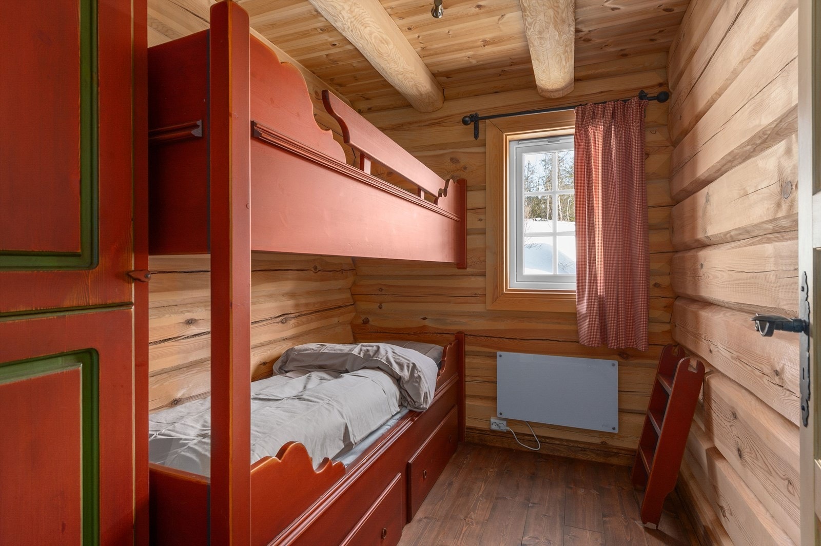 Rød køyeseng og tømmervegger skaper en varm og rustikk atmosfære. Galleribilde