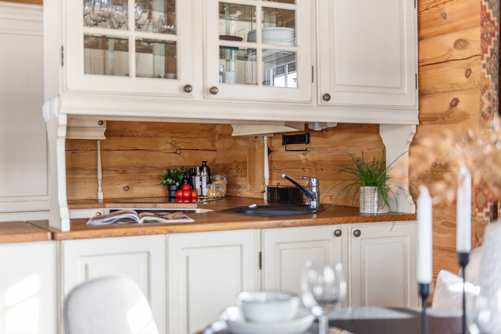 Glasskap over benken gir praktisk oppbevaring og enkel tilgang til servise, mens benkeplaten i tre gir en robust arbeidsflate. Galleribilde