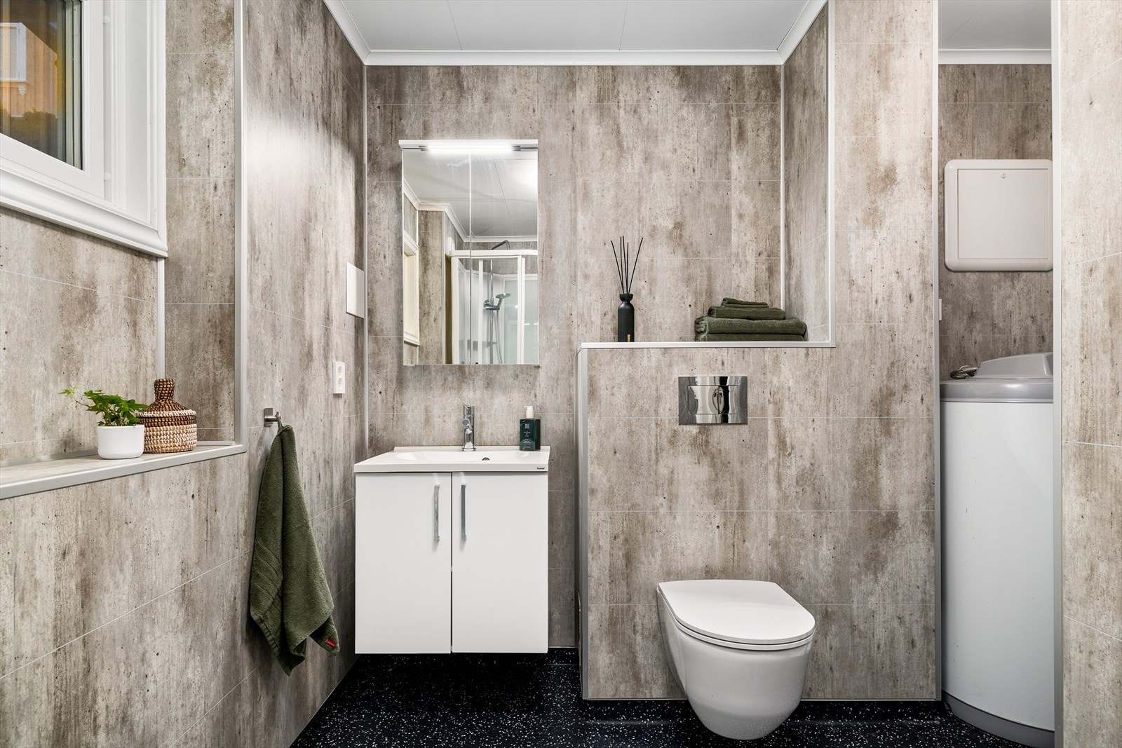 Moderne og stilrent bad i grå fargetoner med vegghengt WC samt servant med speil og innredning. Galleribilde