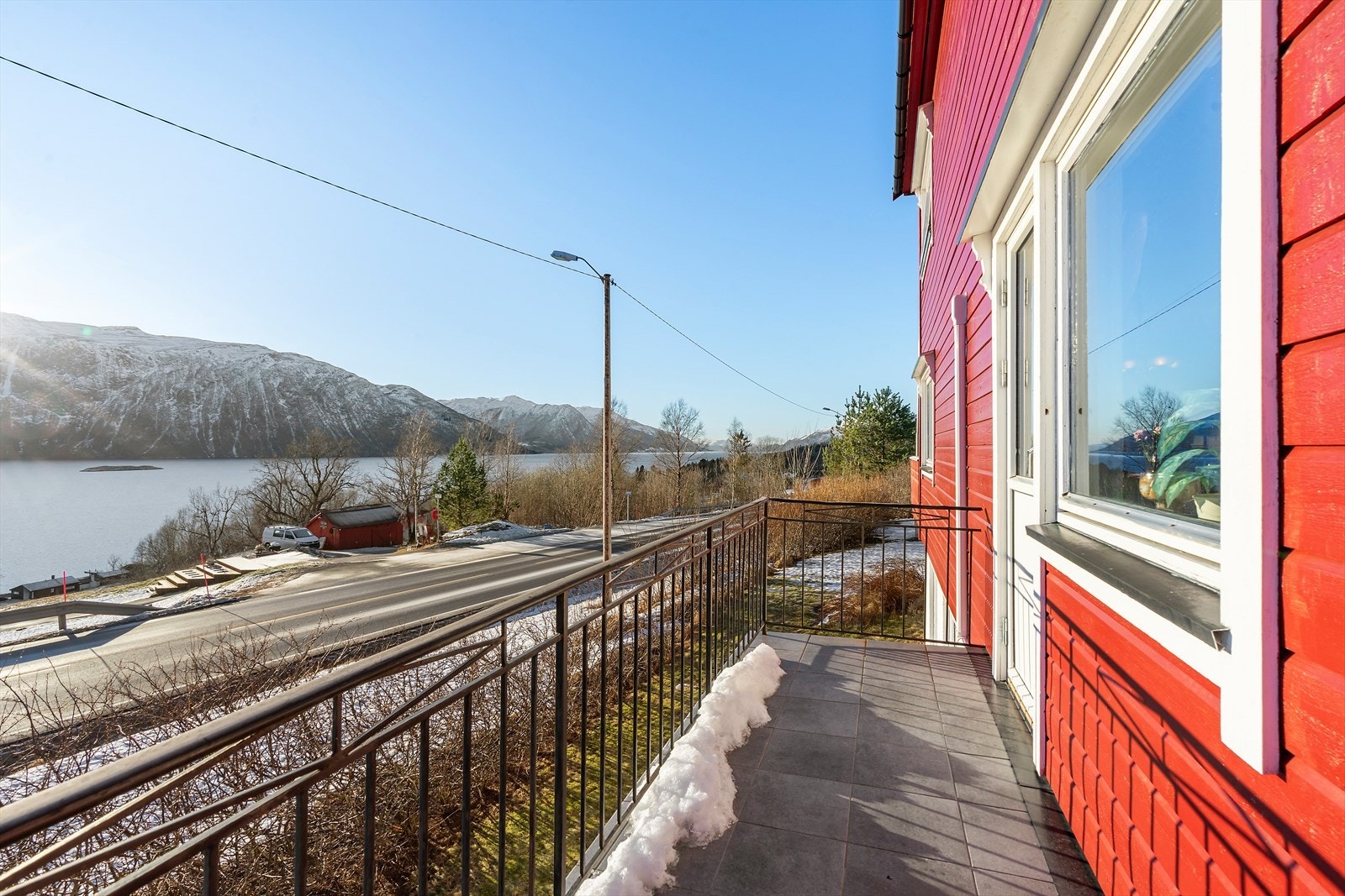 Sørvendt veranda i betong har flislagt dekke og rekkverk i stål, med adkomst fra både stue og inngangspartiet. Galleribilde