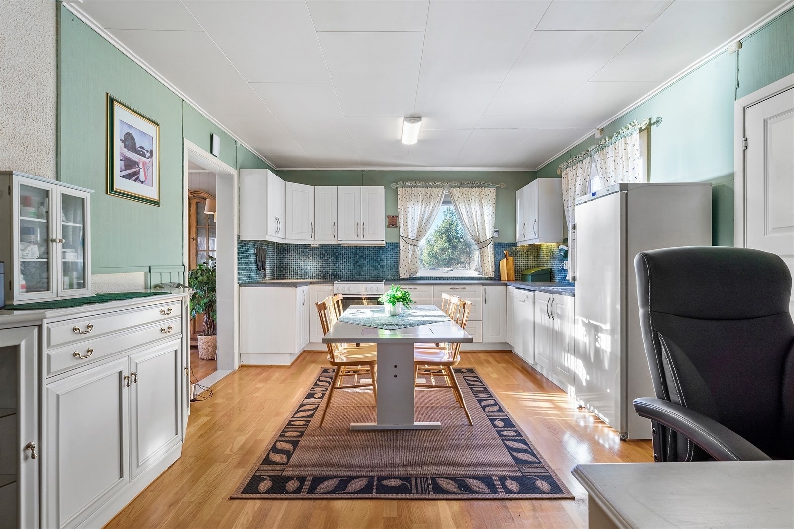 Kjøkkenet i første etasje har parkettgulv og profilerte fronter fra 2007, samt fliser mellom benkeplate og overskap. Galleribilde