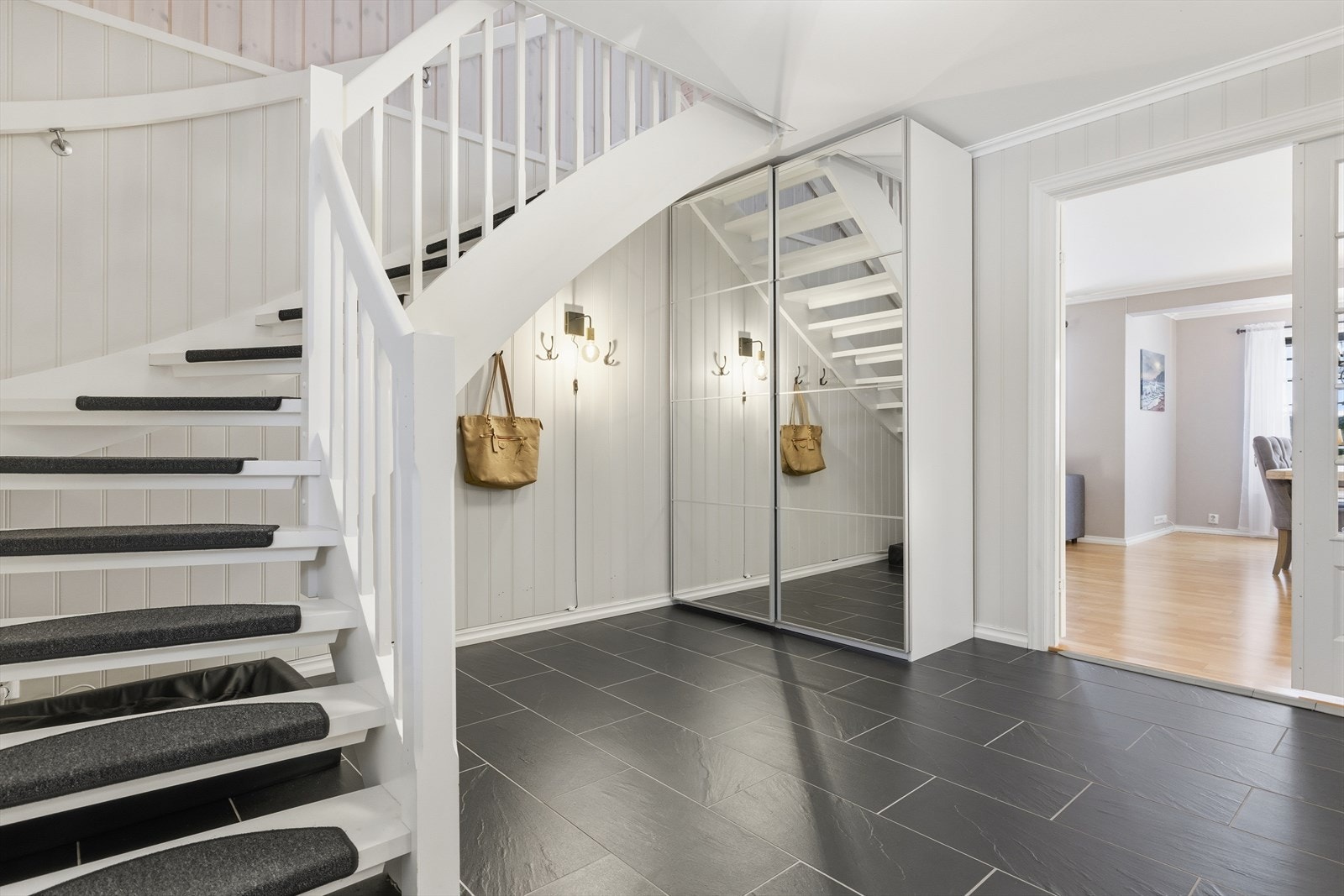 Velkommen inn til en lys og romslig entré med plass for oppheng av yttertøy og til å sette ifra seg sko. Galleribilde