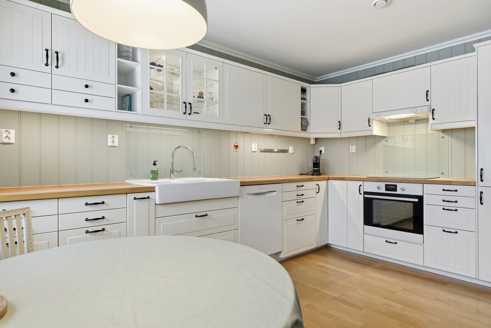 Klassisk kjøkkeninnredning med hvite profilerte fronter og benkeplate av heltre. Galleribilde