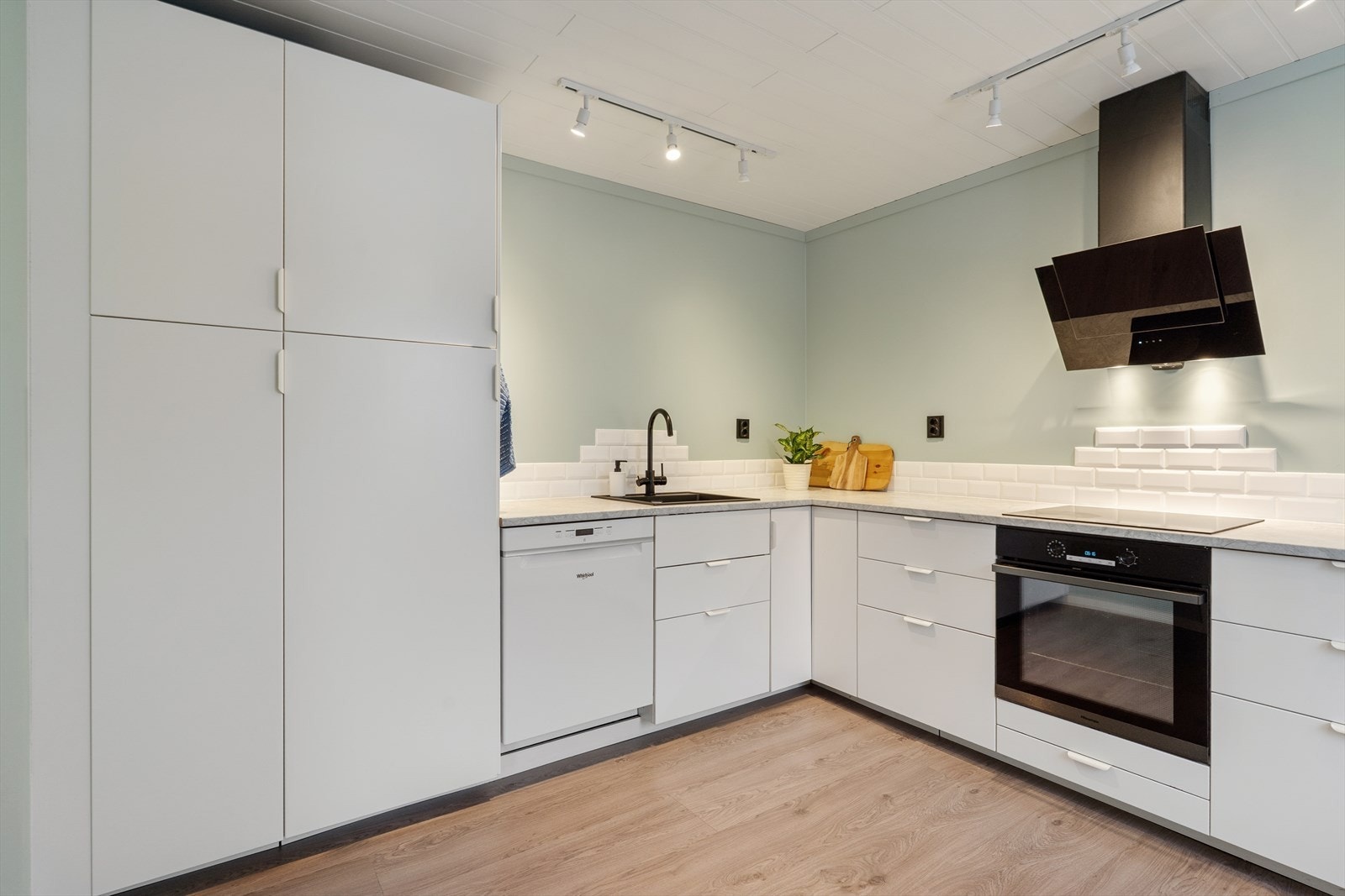 Med integrerte hvitevarer og et moderne utseende innbyr kjøkkenet til matlaging med plass for flere arbeidssoner Galleribilde