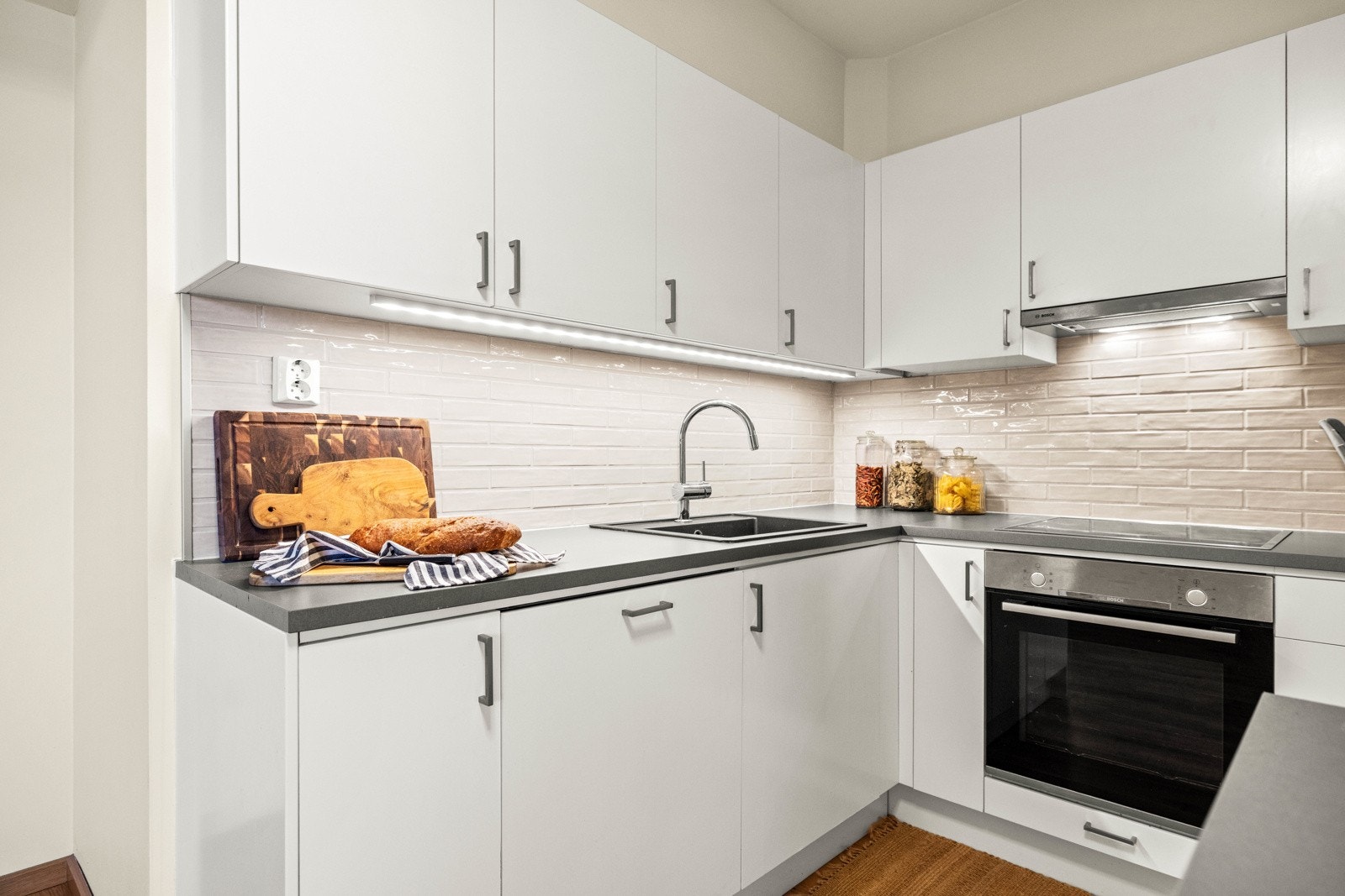 Kjøkkenet har slette fronter, laminat benkeplate og fliser mellom benk og overskap. Galleribilde