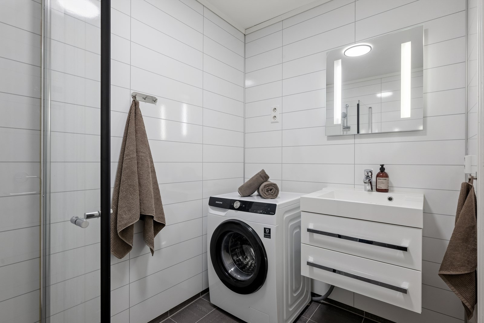 Innredningen består av en servant nedfelt i baderomsmøbel, et veggmontert toalett og et dusjhjørne med dusjvegger. Galleribilde