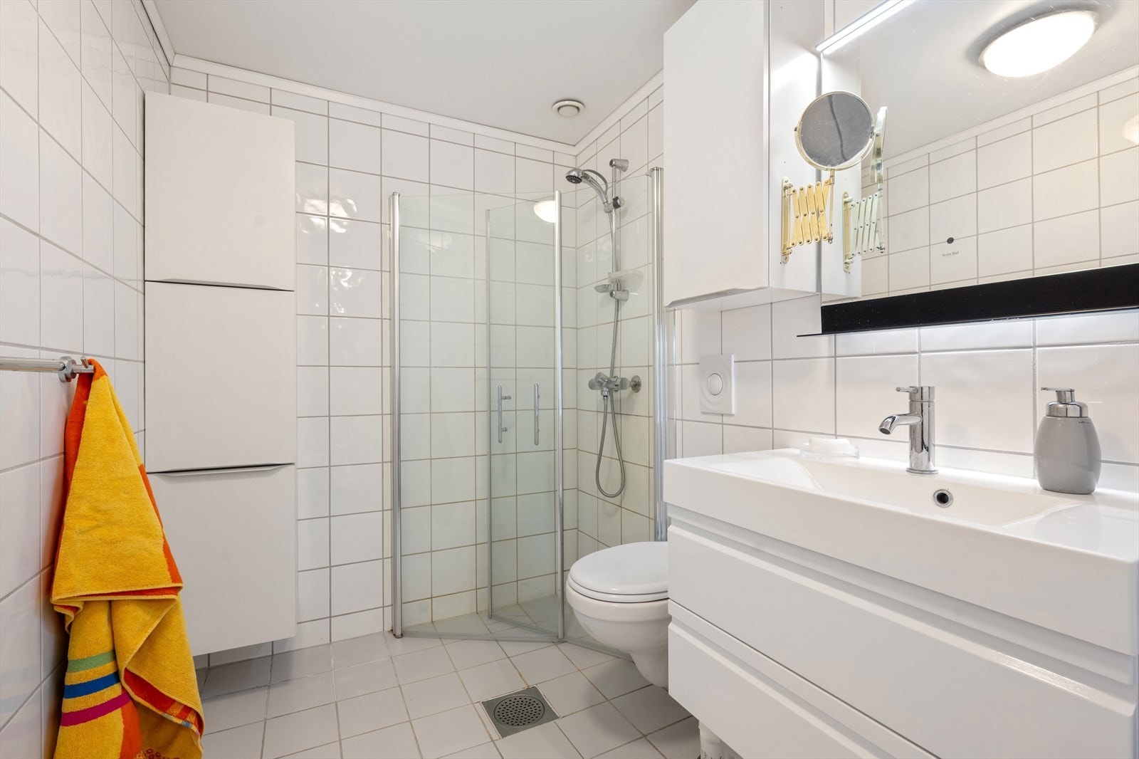 Boligens bad er flislagt med elektriske varmekabler i gulvet. Det er god plass til oppbevaring i både benkeskap og veggskap. Galleribilde