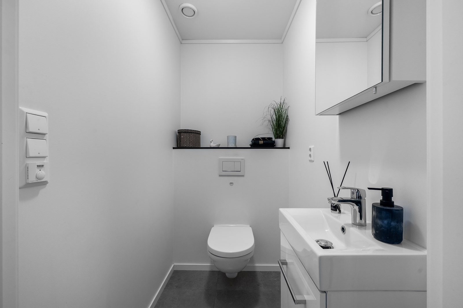 Toalettrommet har veggmontert wc og servant med speil over, samt flislagt gulv. Galleribilde