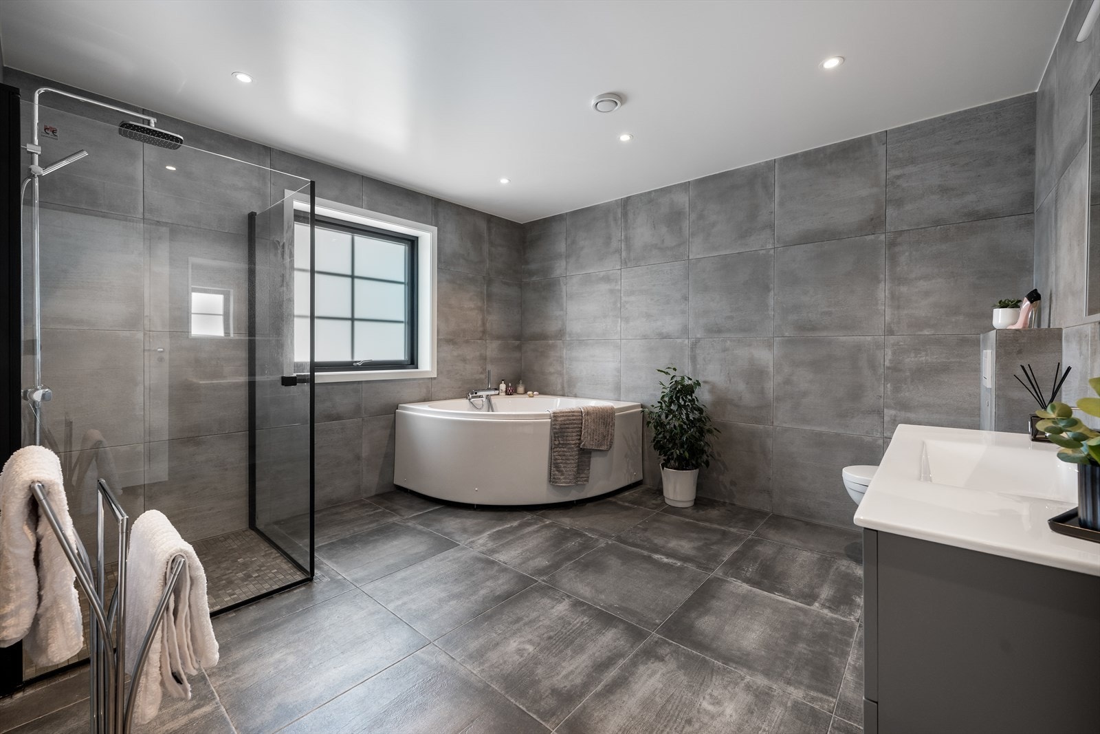 Baderom i andre etasje er innredet med badekar og dusjhjørne med glassdører. Det er servant med møblement og vegghengt toalett. Downlights i himling for en behagelig belysning. Galleribilde