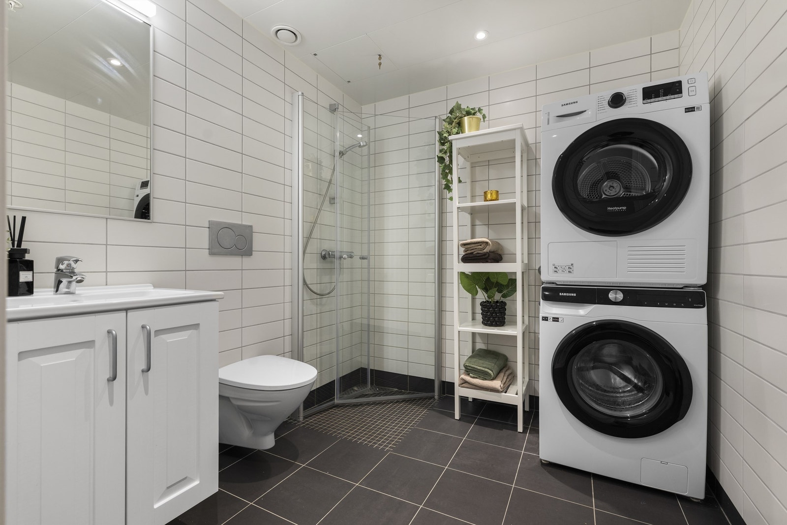 Flislagt og moderne baderom med vegghengt toalett og dusjhjørne. Galleribilde