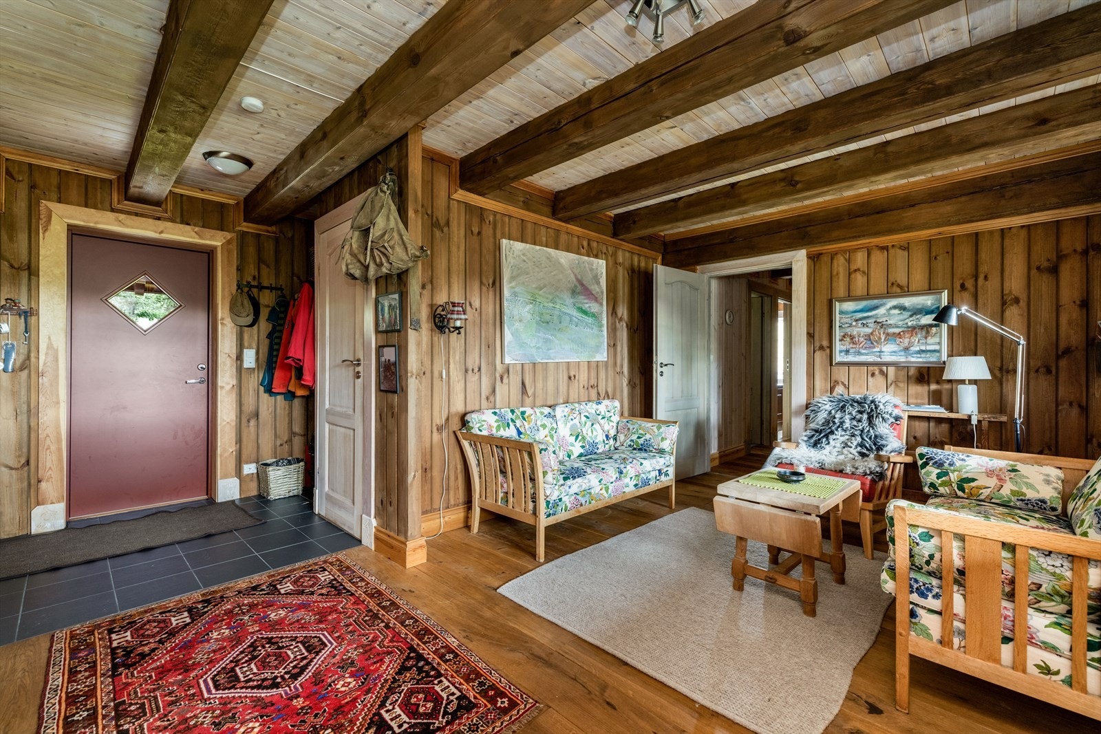 Romslig entré med åpen løsning til tv-stue. I entré er det flislagt gulv og fin nisje for oppbevaring av sko- og yttertøy. Galleribilde