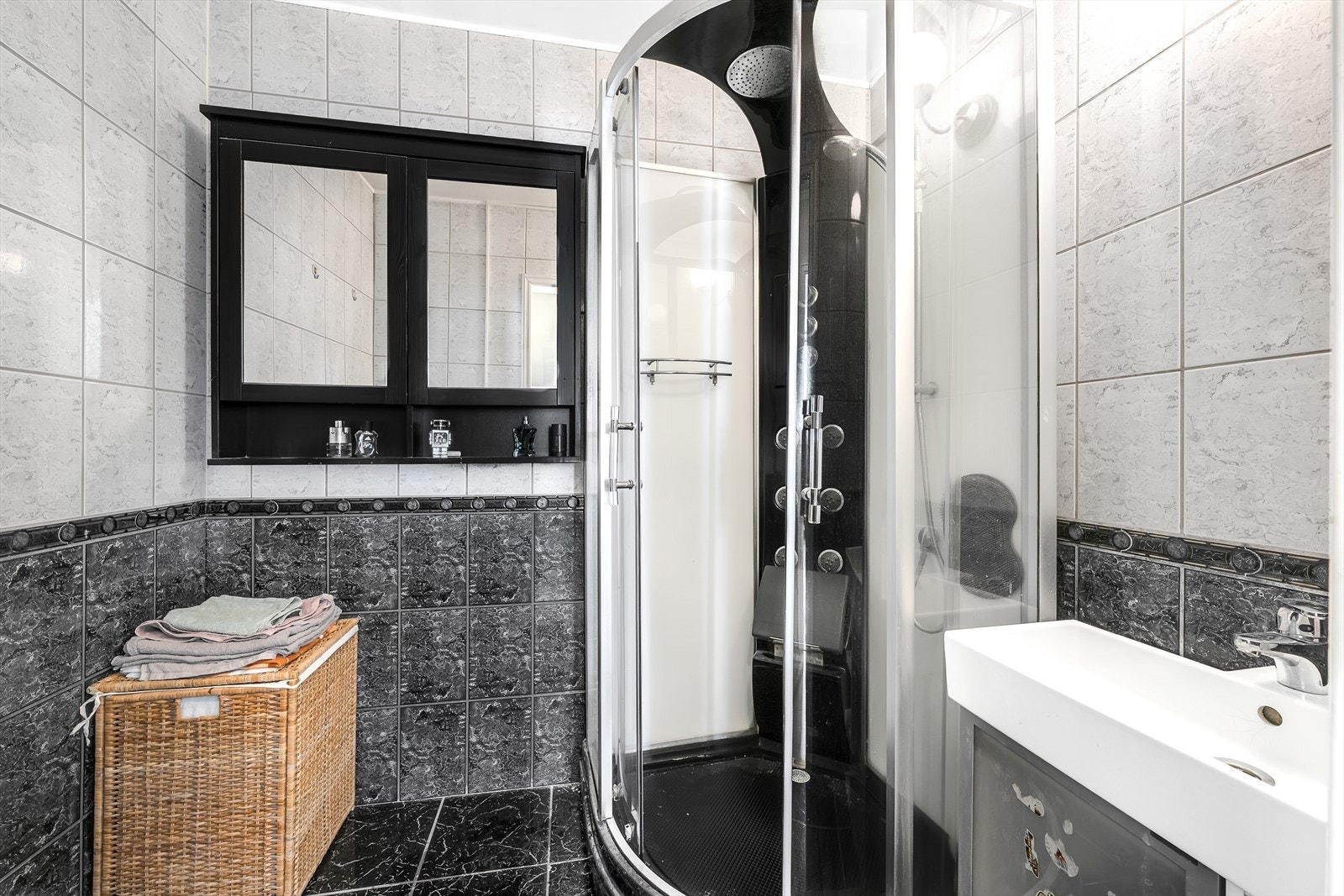 Pent flislagt bad med varmekabler i gulv. Innredet med dusjkabinett, servantskap og skap med speil.. Galleribilde