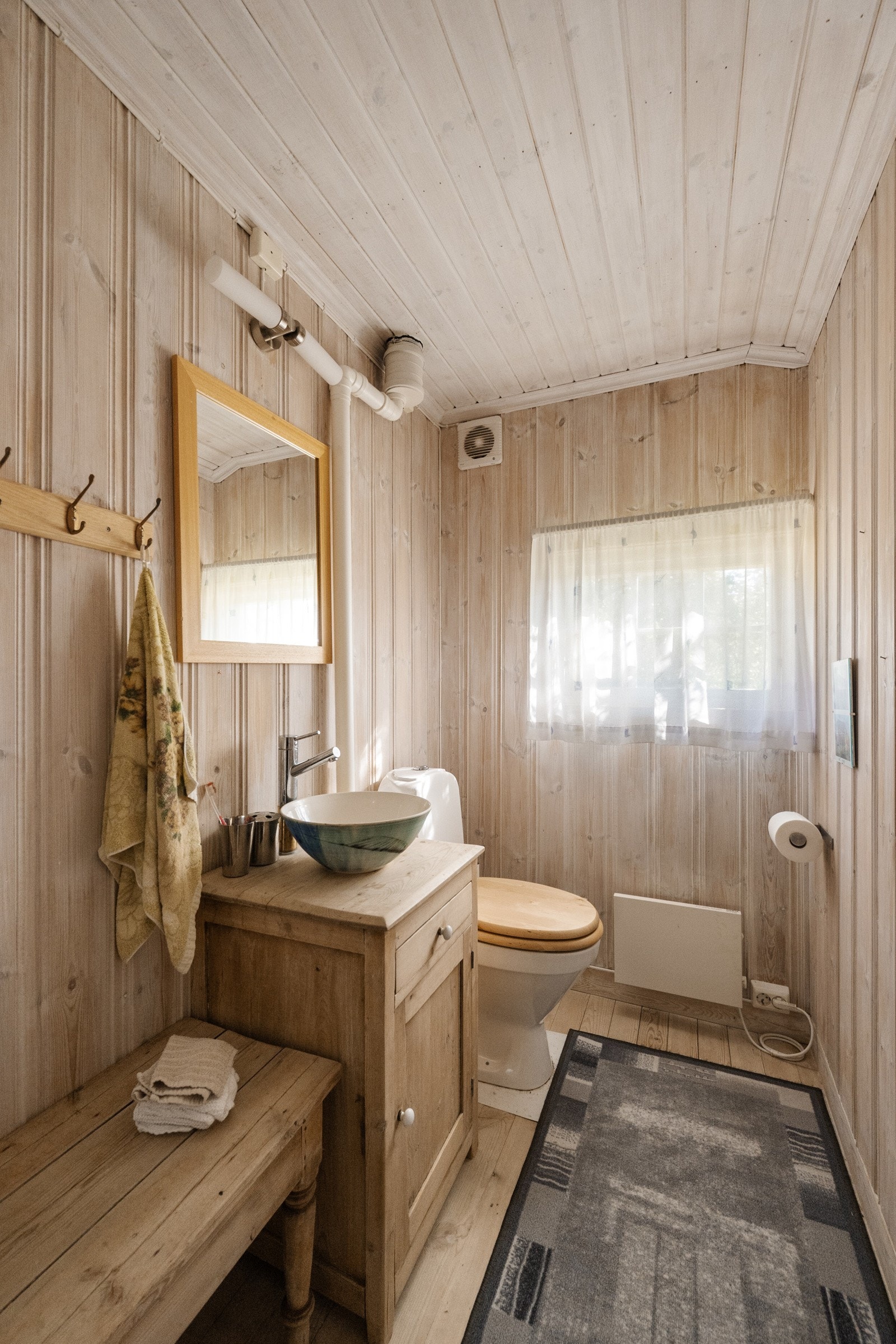 Toalettrommet har overflater av heltre og trepanel som gir en varm og rustikk atmosfære Galleribilde