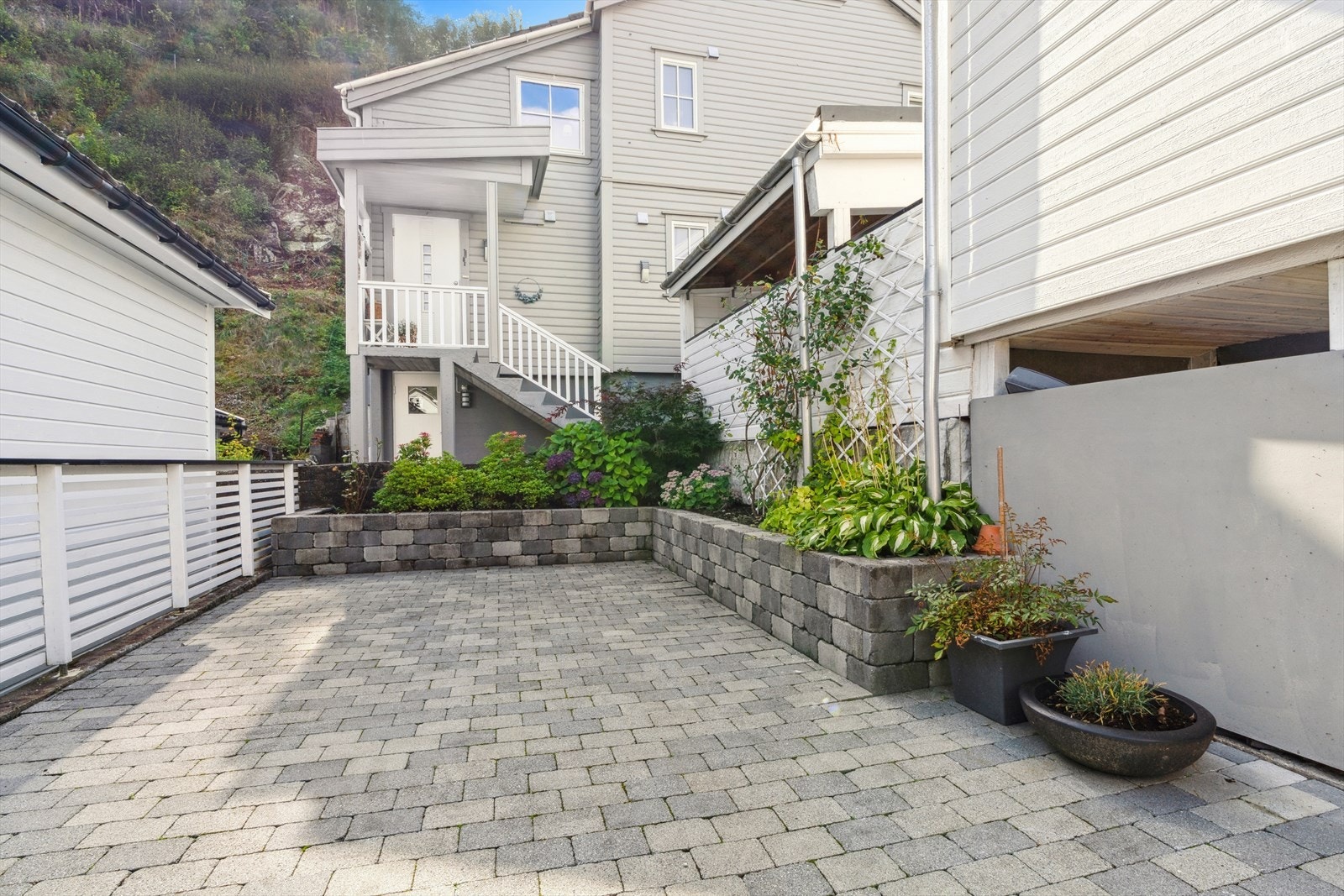 Tomten er opparbeidet med asfalter gårdsrom, uteområde med belegningsstein, diverse beplantinger og terrasseareal. Galleribilde