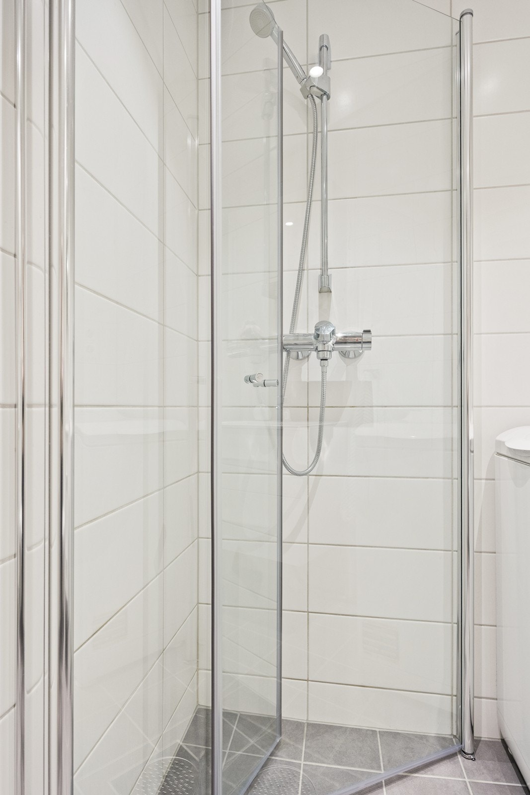 Rommet er utstyrt med dusj med glassdører, vegghengt toalett og servantinnredning. Galleribilde