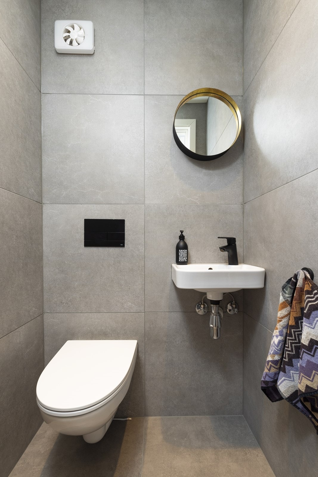 Separat wc-rom med vegghengt toalett og enkel servant på vegg. Galleribilde