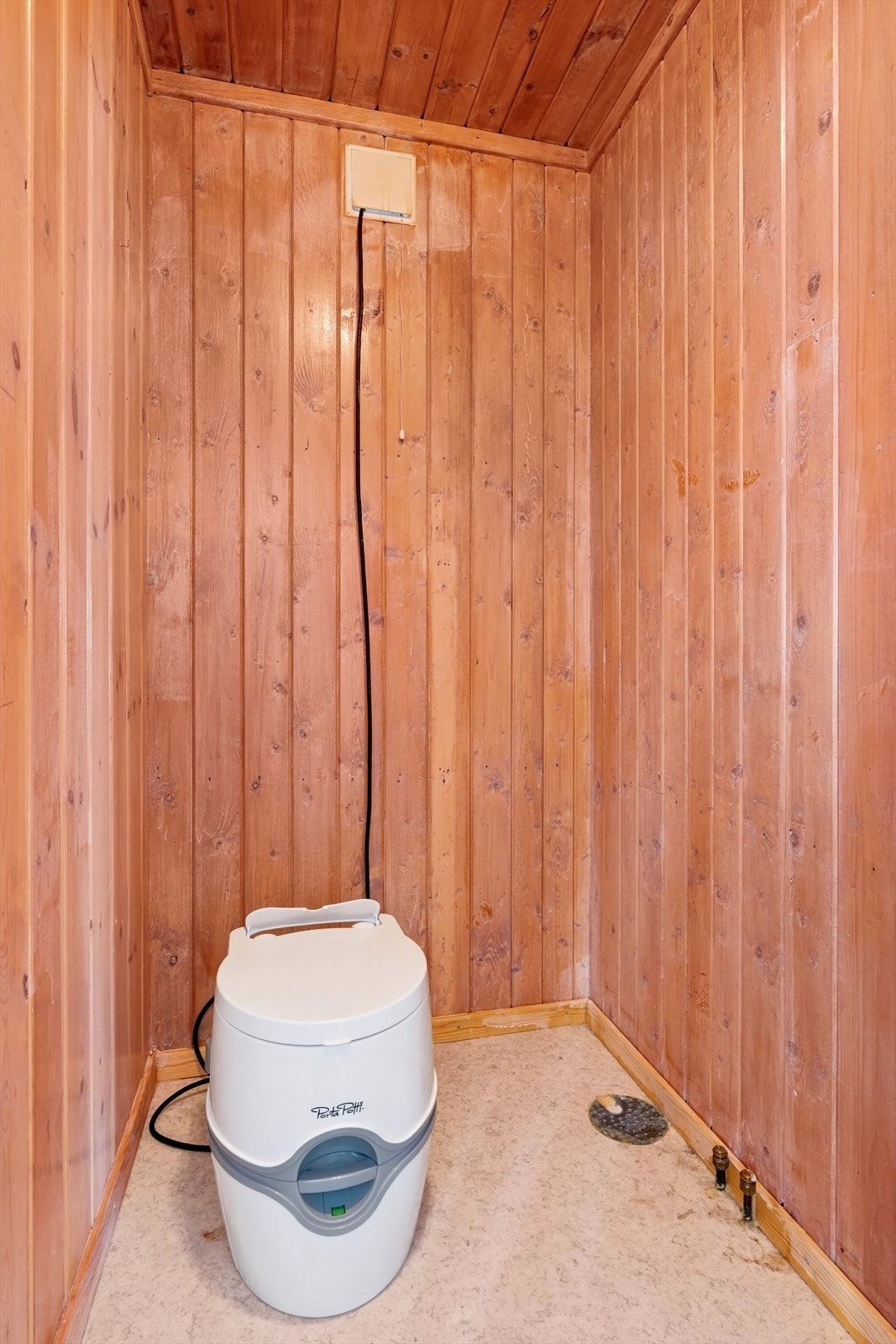 Dorom med belegg på gulv og panel på vegger med adkomst fra soverom, utstyrt med porta potti. Galleribilde