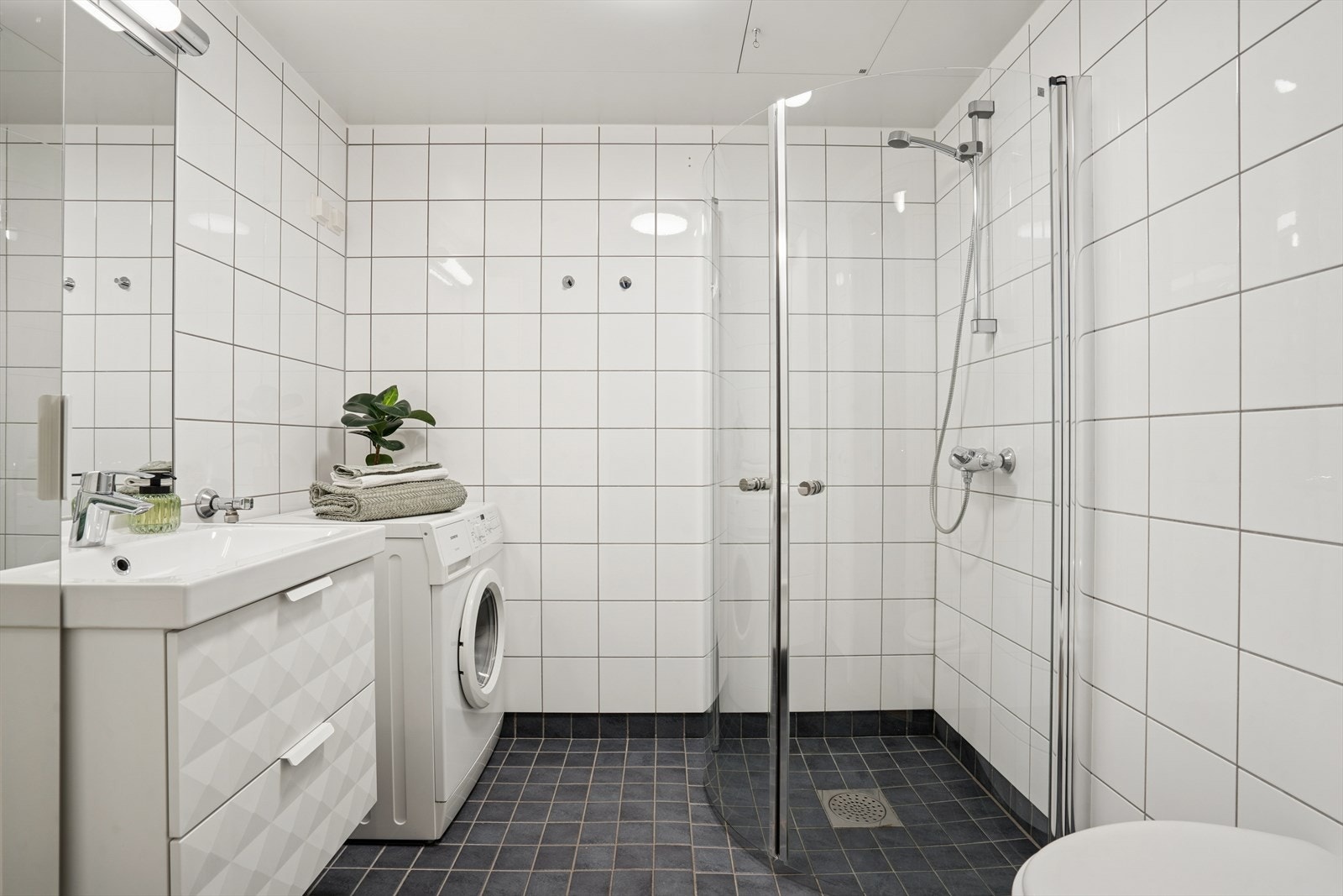 Badet fremstår lyst og romslig, og ble oppgradert med nye innfellbare dusjdører i 2016 og ny servant og blandebatteri i 2018. Galleribilde