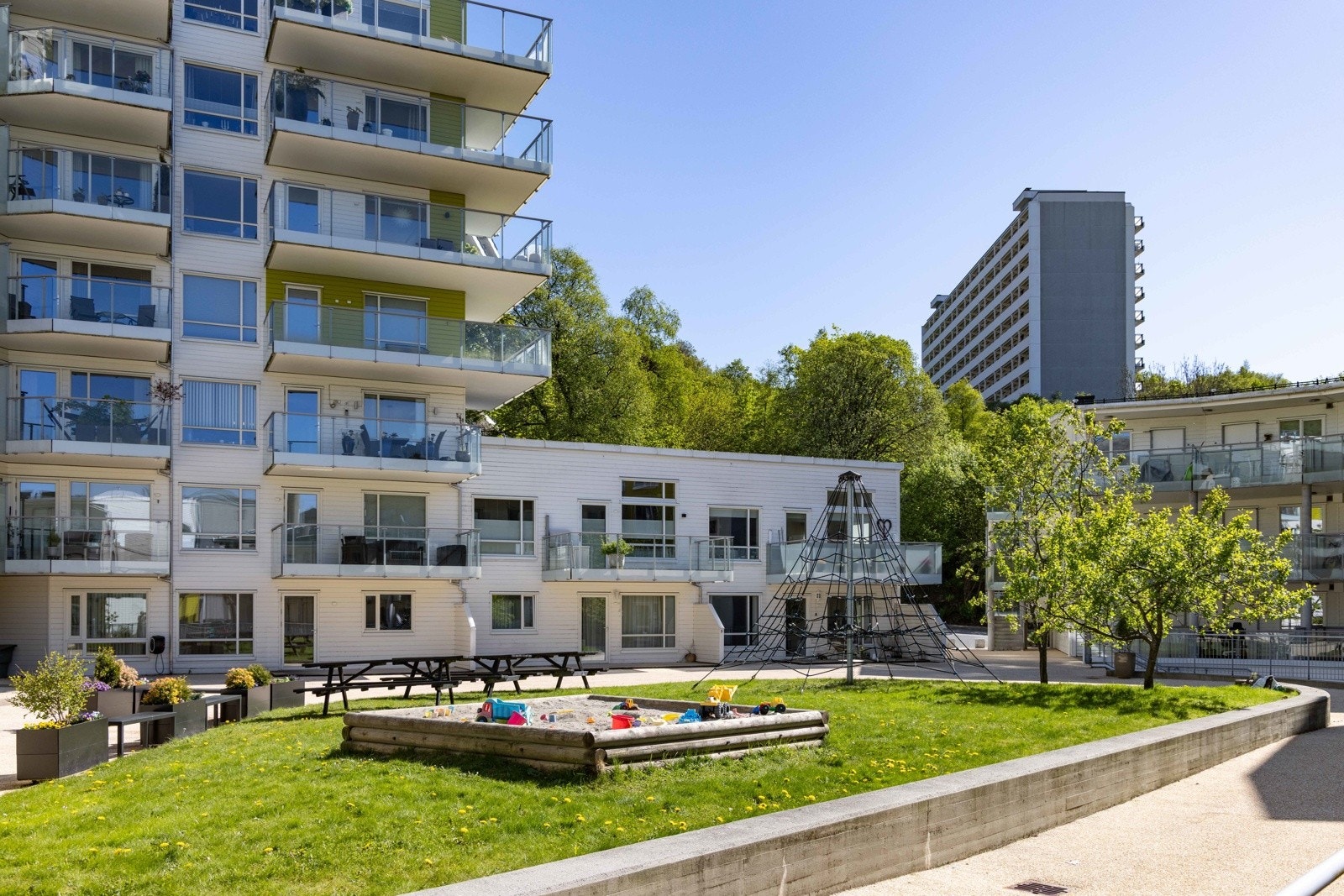 Tre bygg samlet rundt et grønt og trivelig atrium. Galleribilde