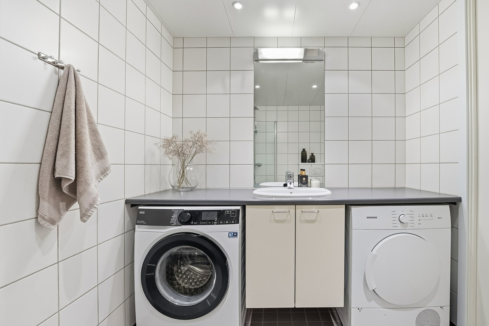 Det er opplegg og plass for vaskemaskin og tørketrommel under praktisk benkeinnredning. Himlingen er lyssatt med downlights. Galleribilde