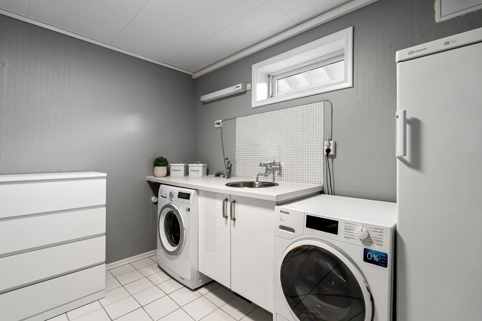 Praktisk vaskerom med opplegg for vaskemaskin, utslagsvask, varmtvannsbereder og elektrisk gulvvarme. Galleribilde