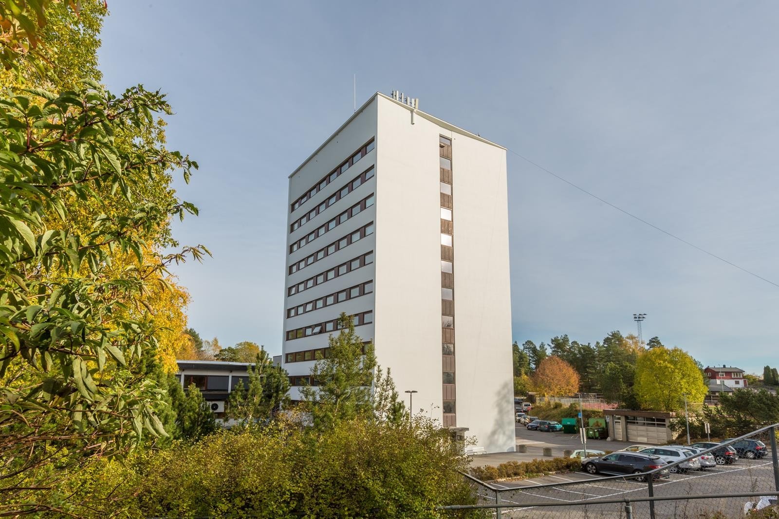 Høyblokk på 10 etasjer med heisadkomst. Parkeringsplass rett utenfor bygget. Galleribilde