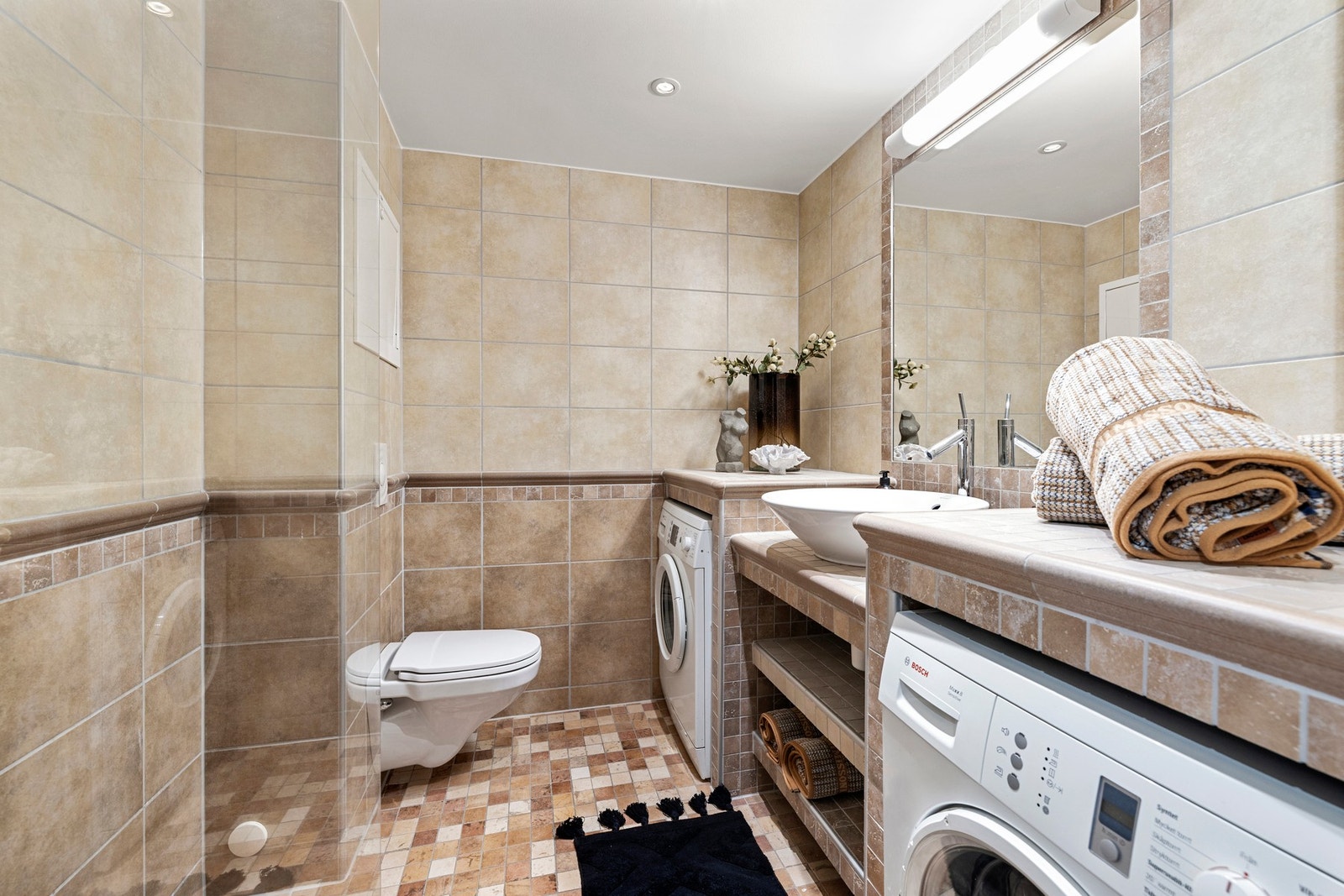 Leiligheten har videre et helfliset bad fra byggeår med gulvvame og nedsenket himling med downlights. Galleribilde