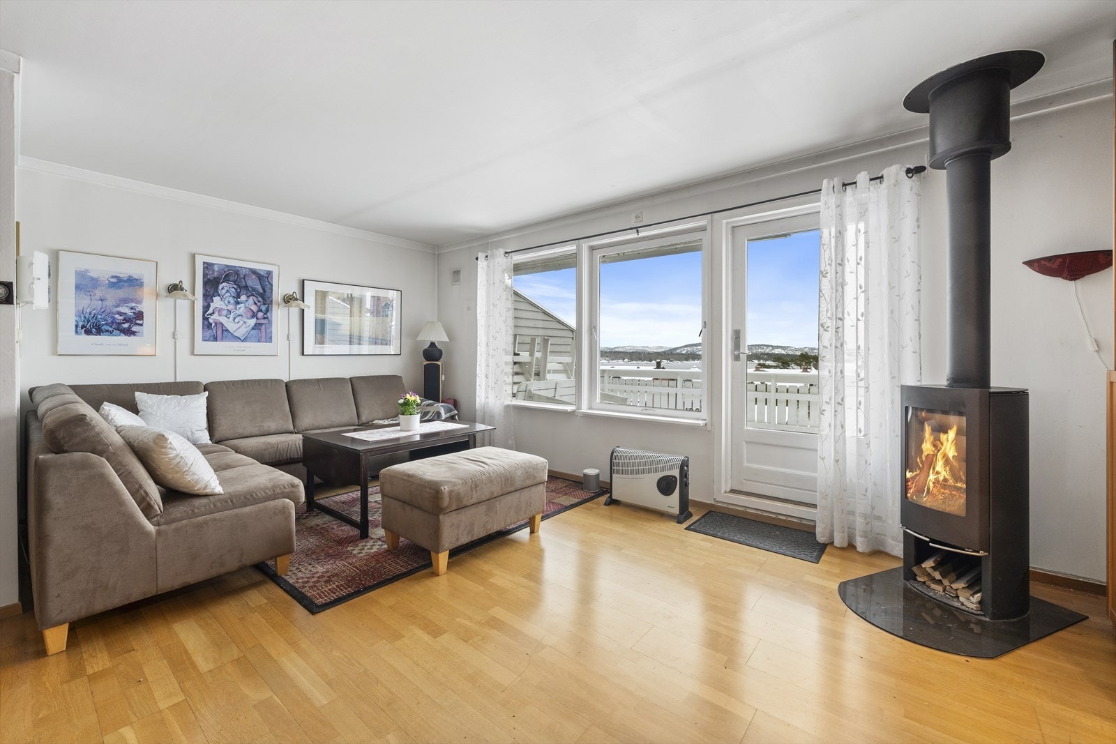 Et stort allrom med vedfyring, sjøutsikt og utgang til terrasse Galleribilde