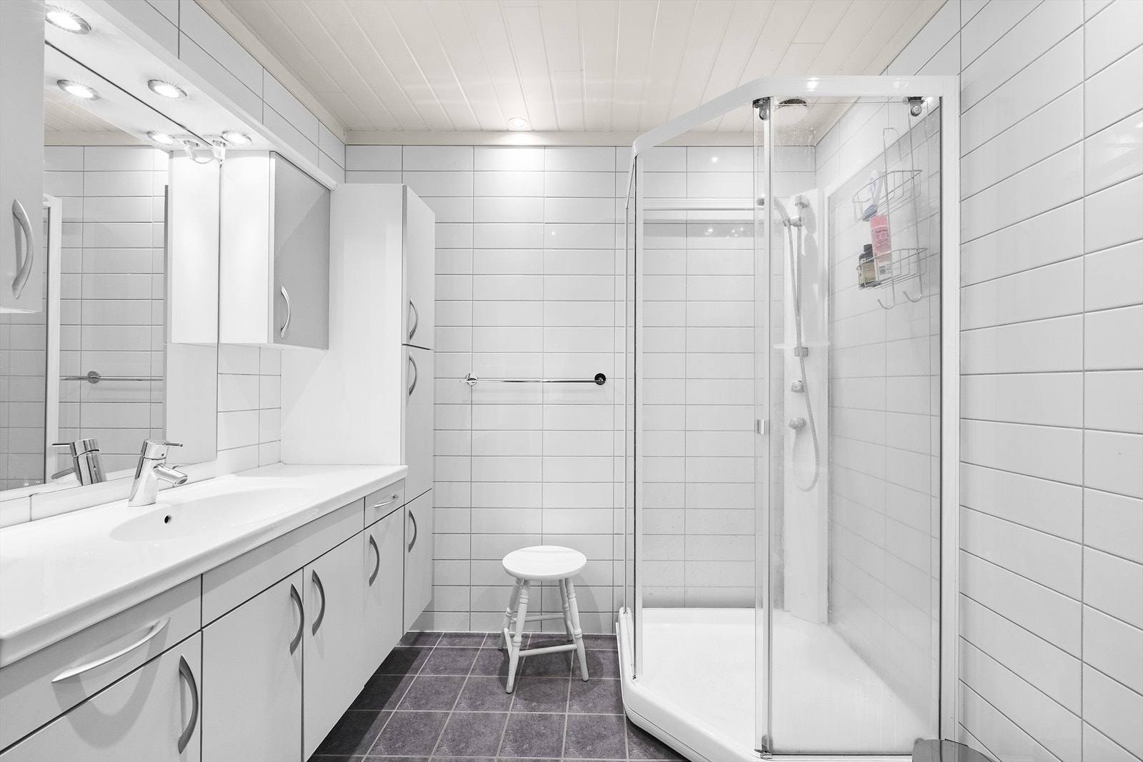 Badet er helfliset og lyst, med stor baderomsinnredning og spotter i tak Galleribilde