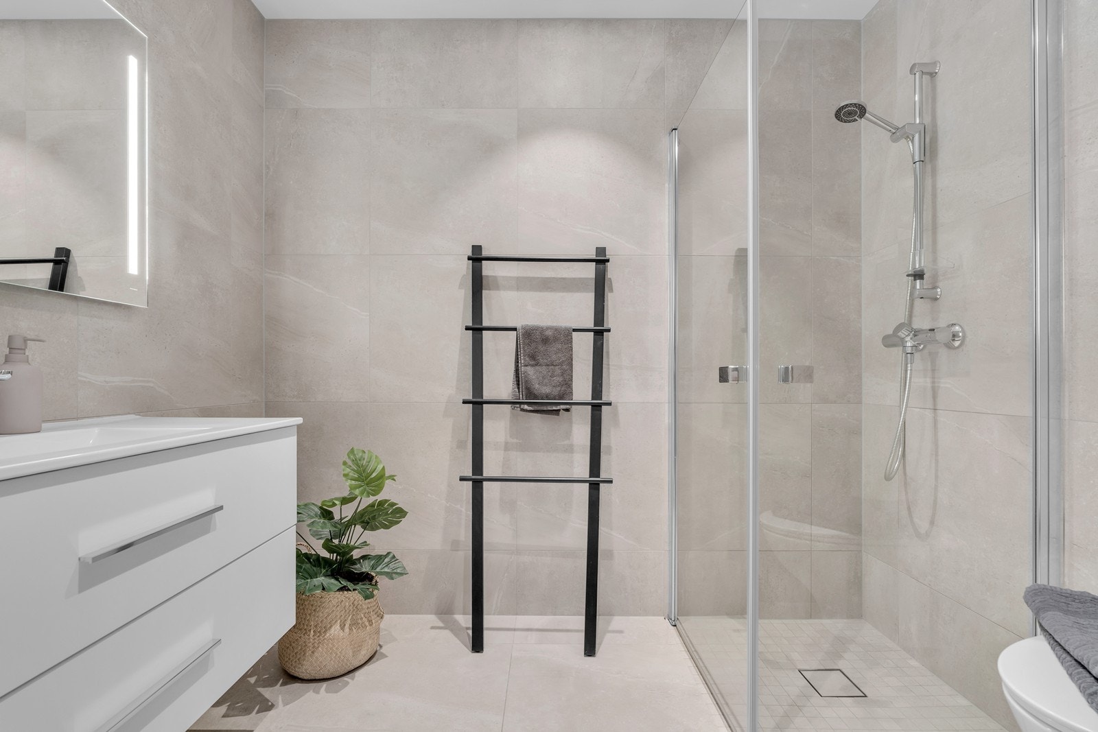 Det største badet har lekre fliser, hvit innredning, dusjhjørne og vegghengt wc. Galleribilde