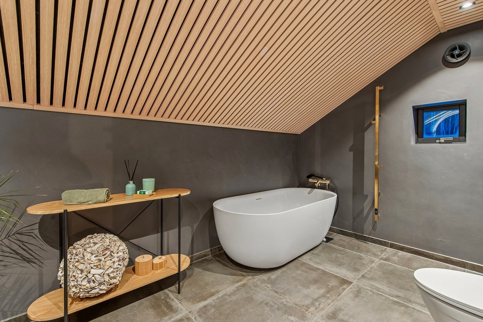 Her er det et frittstående badekar, håndkletørker og elektriske varmekabler i gulvet for ekstra komfort. Galleribilde