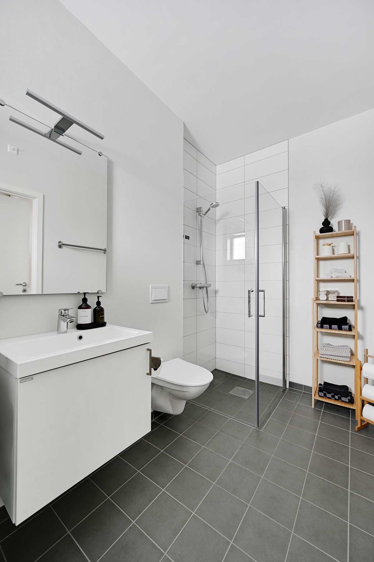 Det er servant i en innredning med underskap og et vegghengt speil med belysning Galleribilde